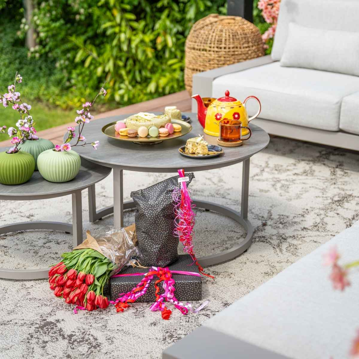 Close up of outdoor table with tea set, gifts, and flowers.