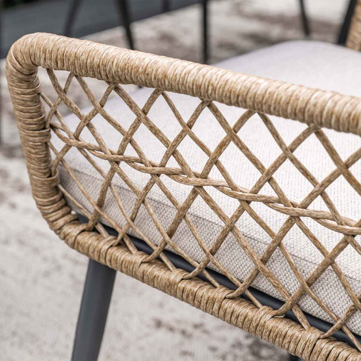 Close-up of a chair back with woven beige rattan and gray cushion.
