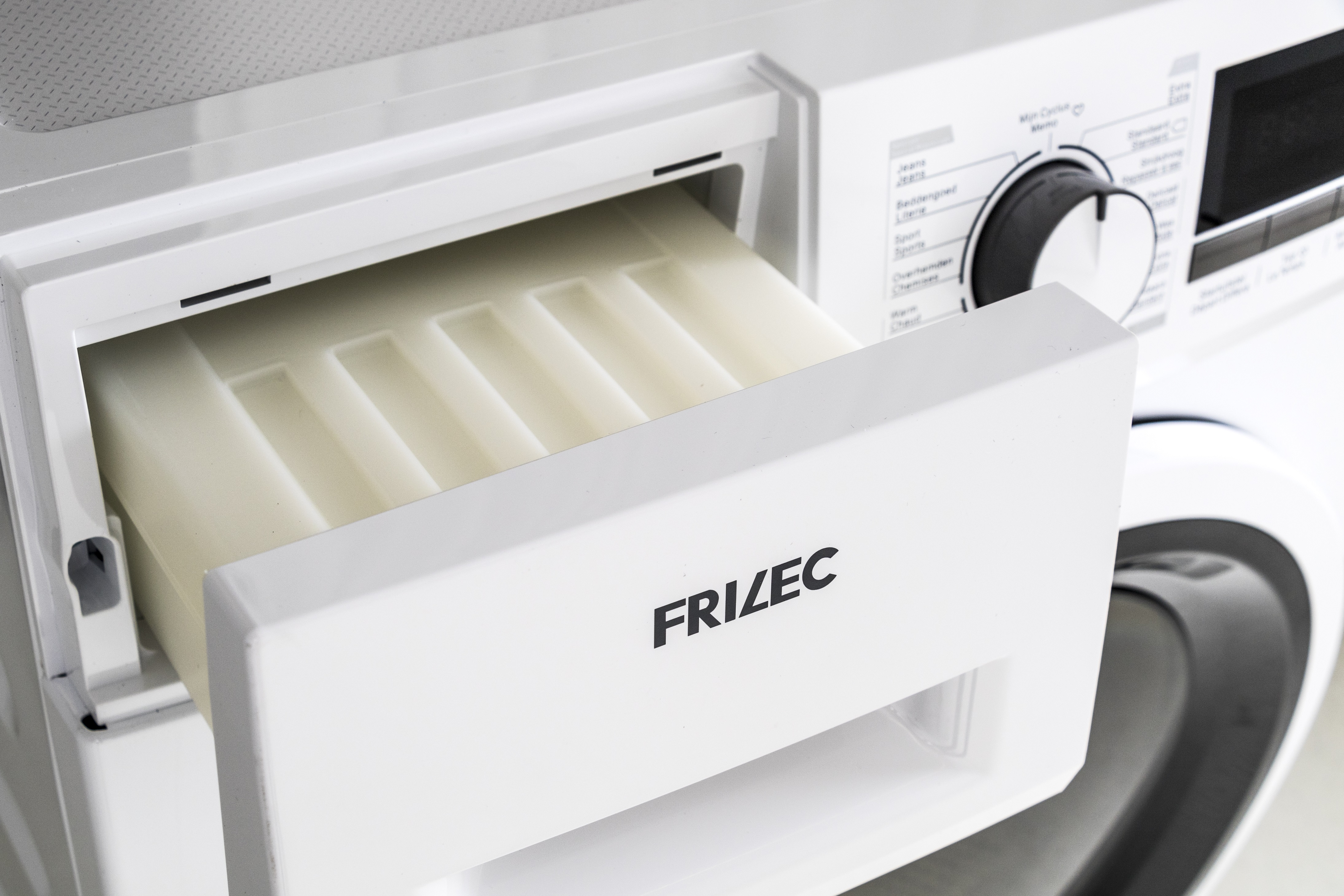 A white Frizec tumble dryer with an open detergent drawer, revealing an empty interior.