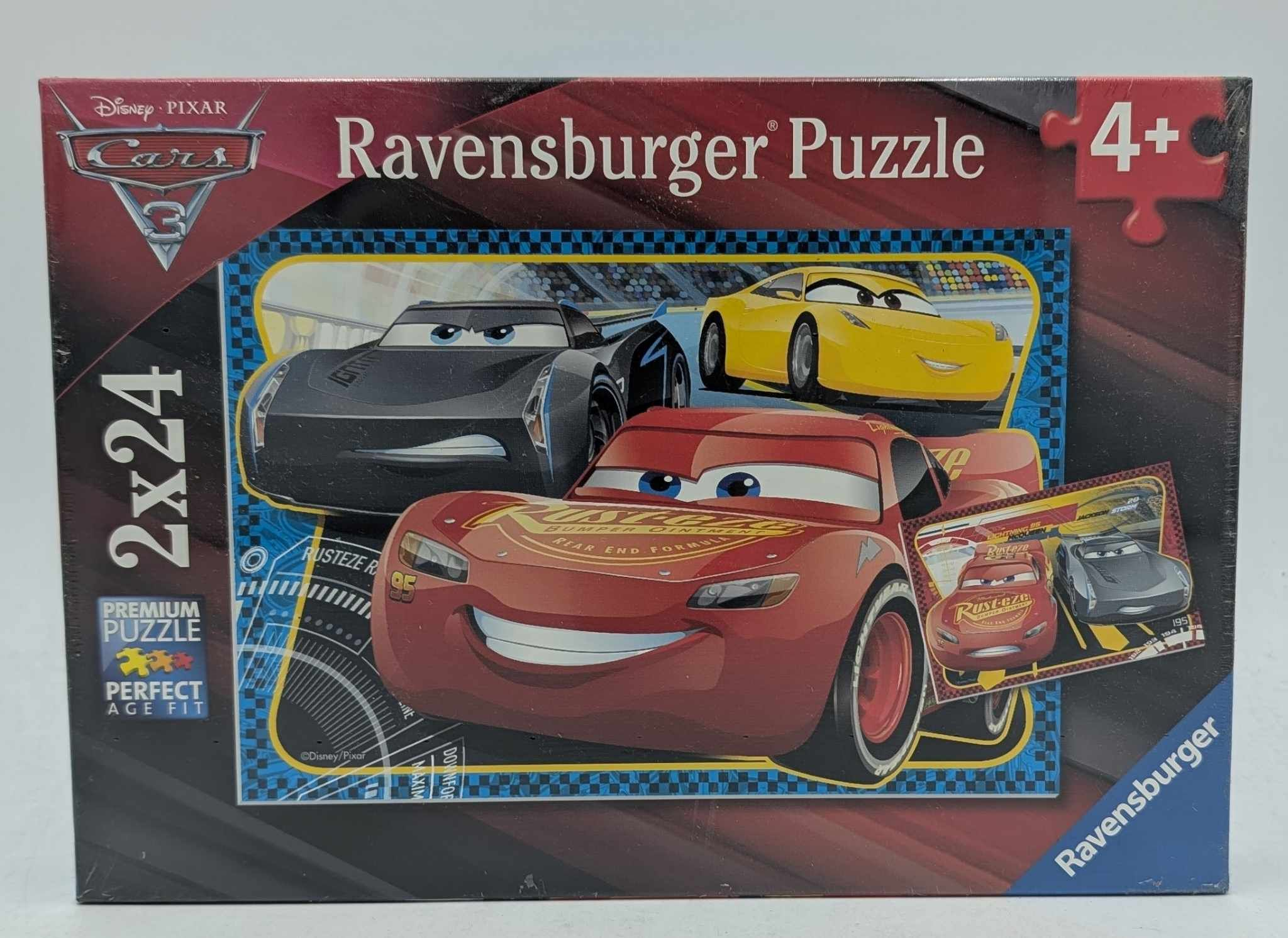 Puzzledose mit Cars 3-Charakteren: Roter Lightning McQueen, schwarze und gelbe Autos. "Ravensburger Puzzle" steht drauf.