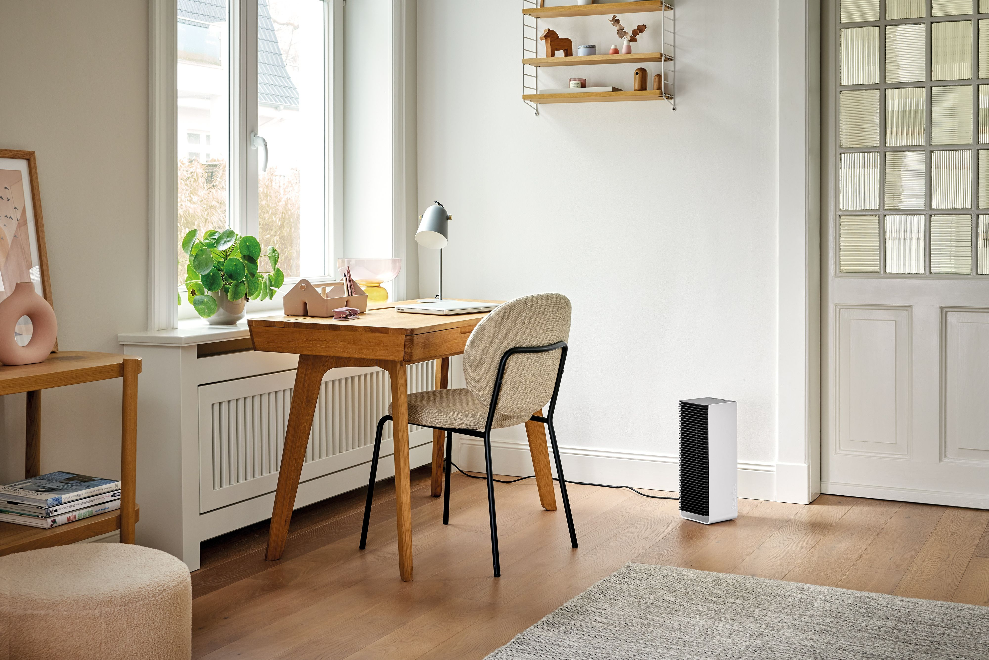Luchtreiniger in een kamer. Bureau, stoel, raam, lamp. Witte luchtreiniger.