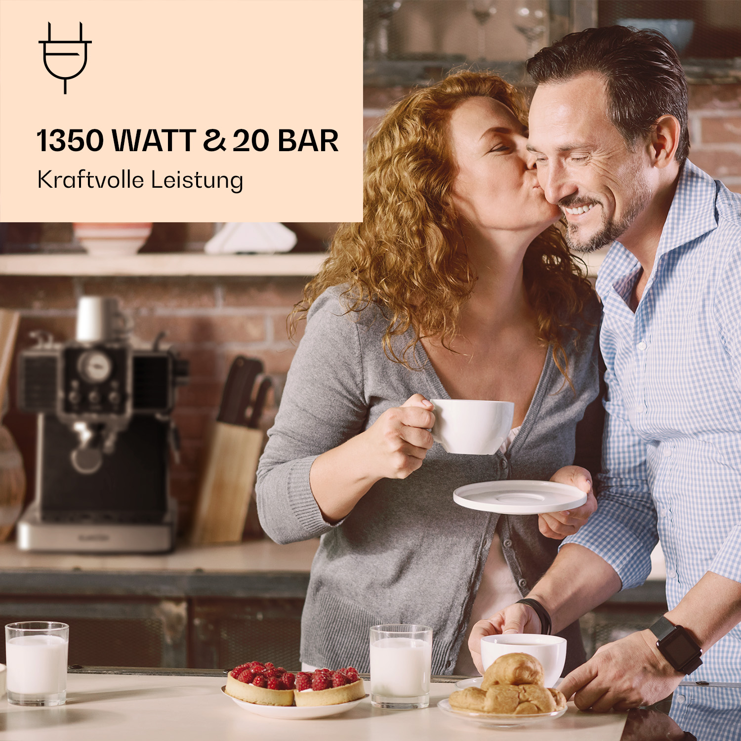 Un uomo e una donna si baciano in cucina. C'è una macchina del caffè sul bancone. Sono presenti articoli per la colazione.