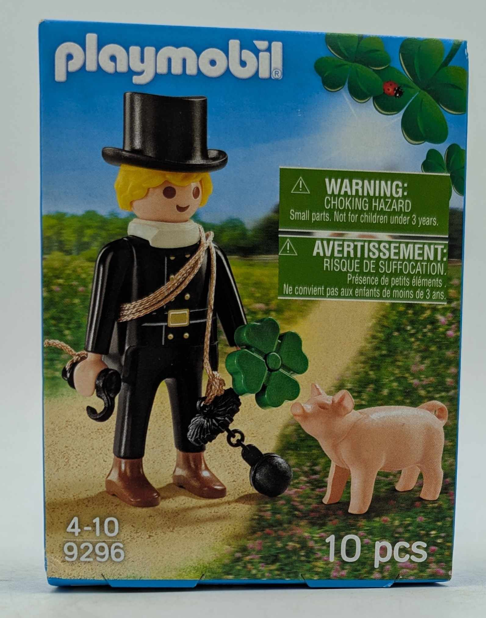 Playmobil-Box: Schornsteinfeger, Schwein und Klee. Warnhinweis. Grüner Hintergrund.