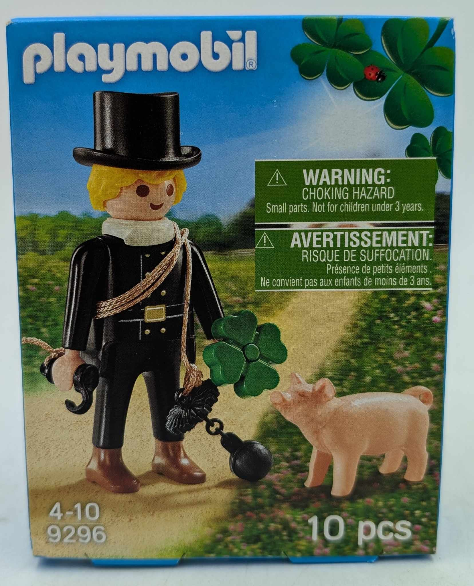 Playmobil-Box: Schornsteinfeger, Schwein und Klee. Warnhinweis. Grüner Hintergrund.