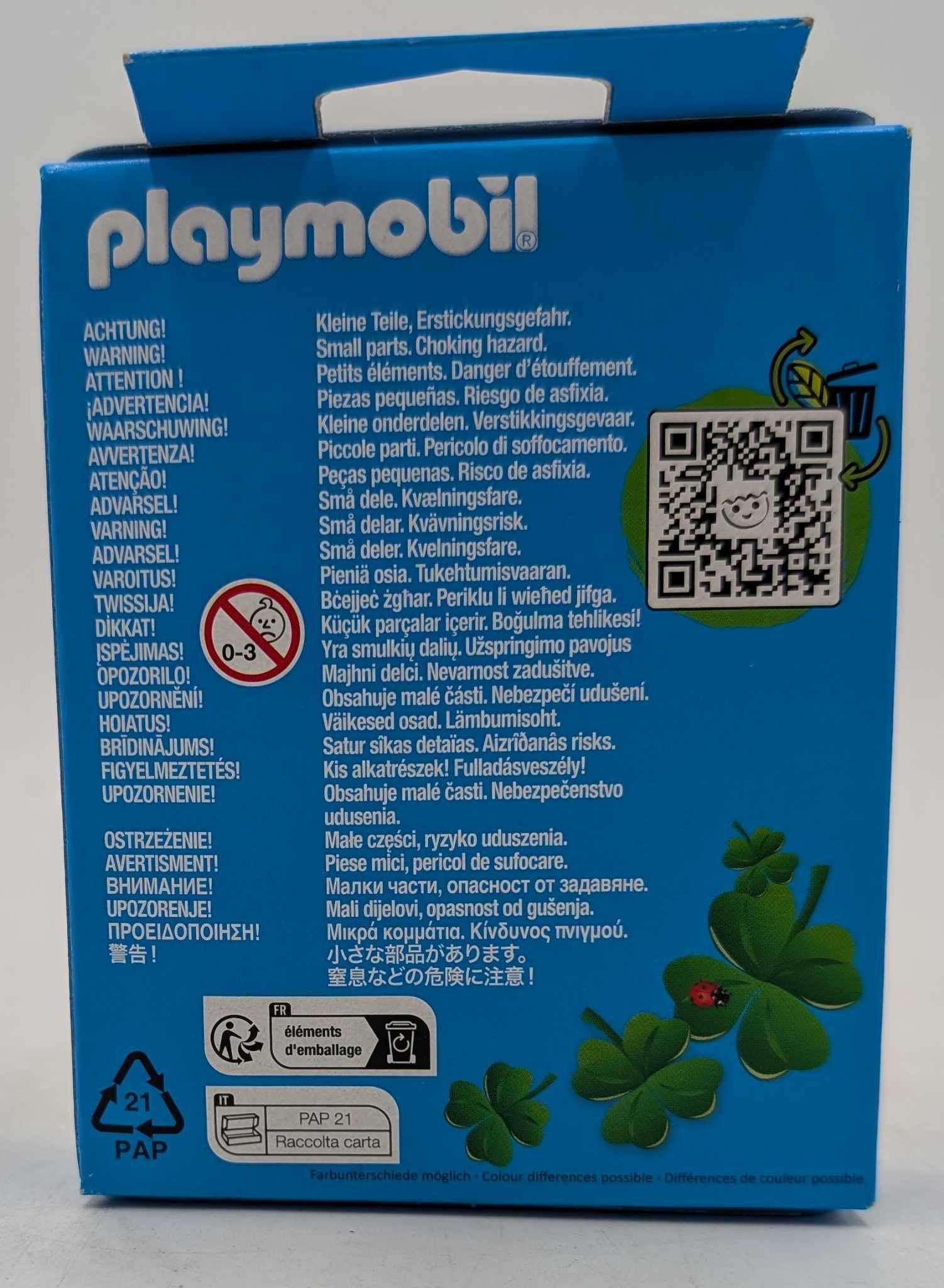 Blaue Playmobil-Box mit Warnhinweisen in mehreren Sprachen. Enthält ein Erstickungsgefahr-Symbol und grüne Kleeblatt-Illustrationen.