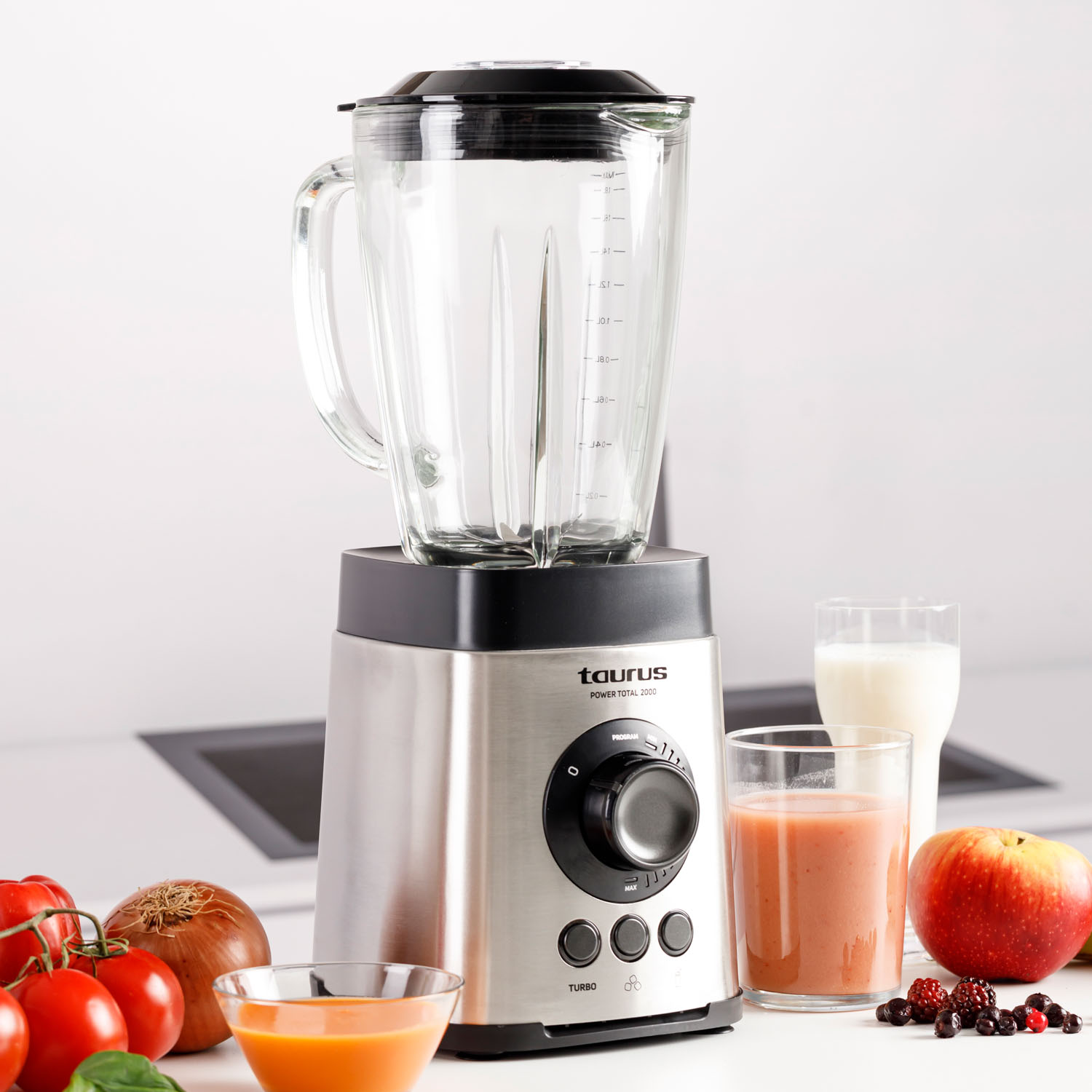 Una licuadora con fruta, verduras, zumo y leche en una encimera blanca. Licuadora Taurus.