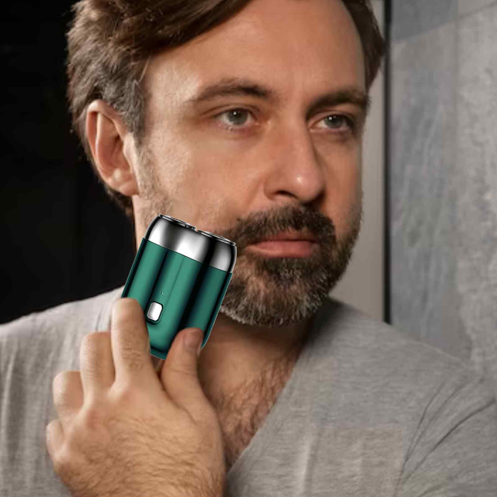 Mann rasiert sich mit einem grün-silbernen Elektrorasierer im Spiegel. Er hat einen Bart.