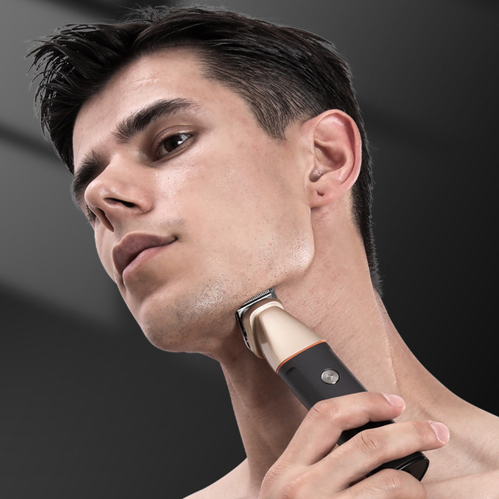 Ein Mann rasiert sich mit einem Trimmer den Hals. Der Trimmer ist schwarz und goldfarben. Der Mann ist oberkörperfrei.