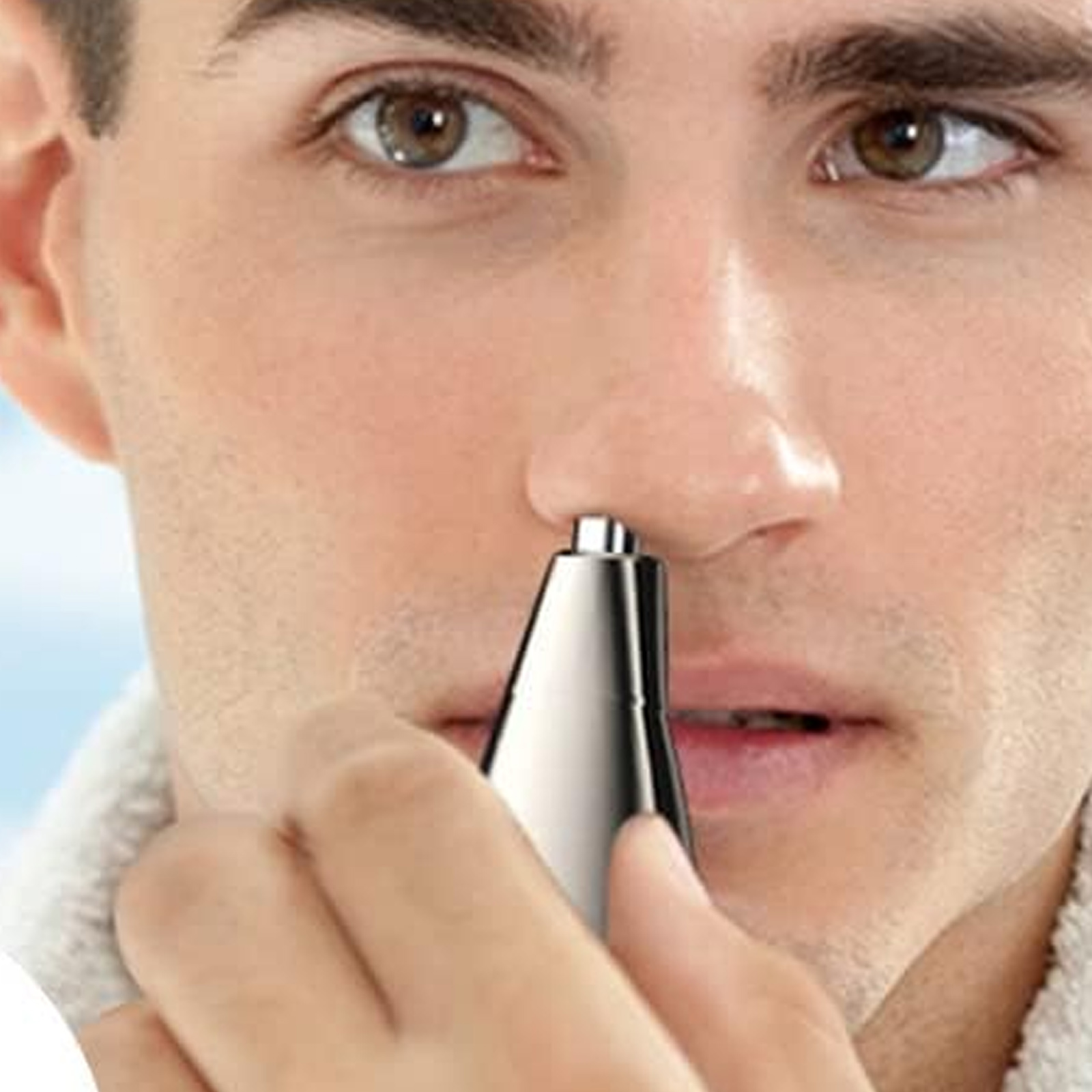 Ein Mann benutzt einen Nasenhaartrimmer. Der Trimmer ist silberfarben, und der Mann ist im Fokus.