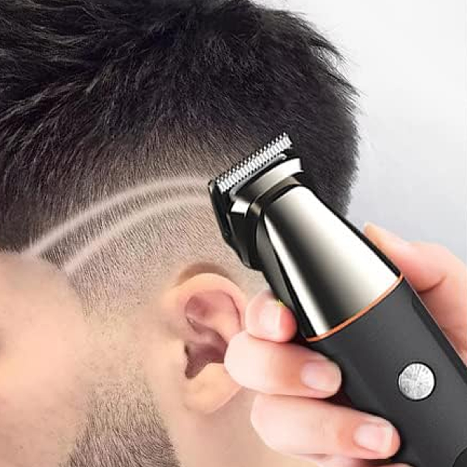 Das Haar eines Mannes wird mit einem elektrischen Trimmer geschnitten. Der Trimmer wird in der Hand gehalten.