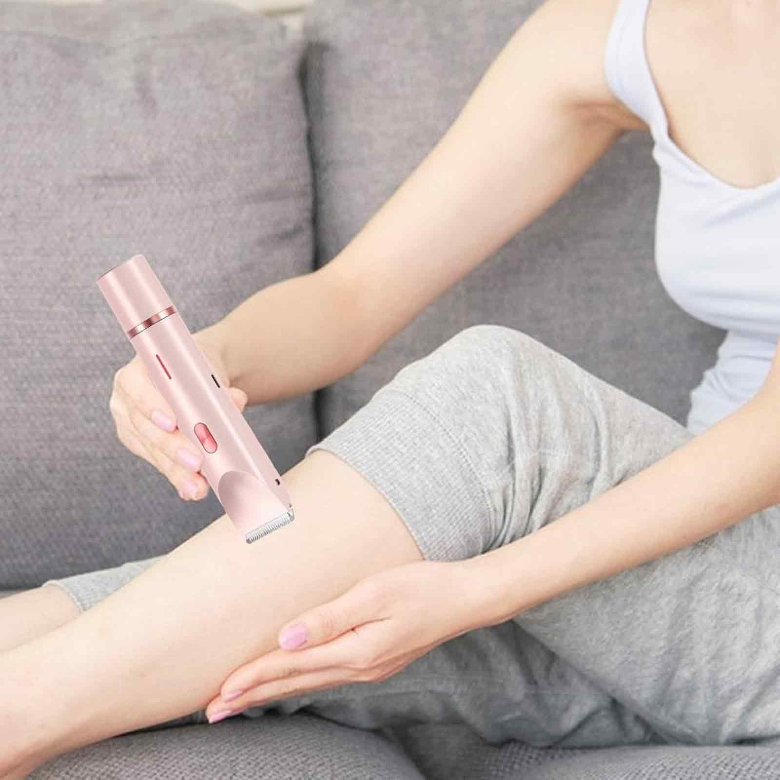 Eine Frau rasiert sich im Sitzen mit einem rosa Elektrorasierer das Bein.