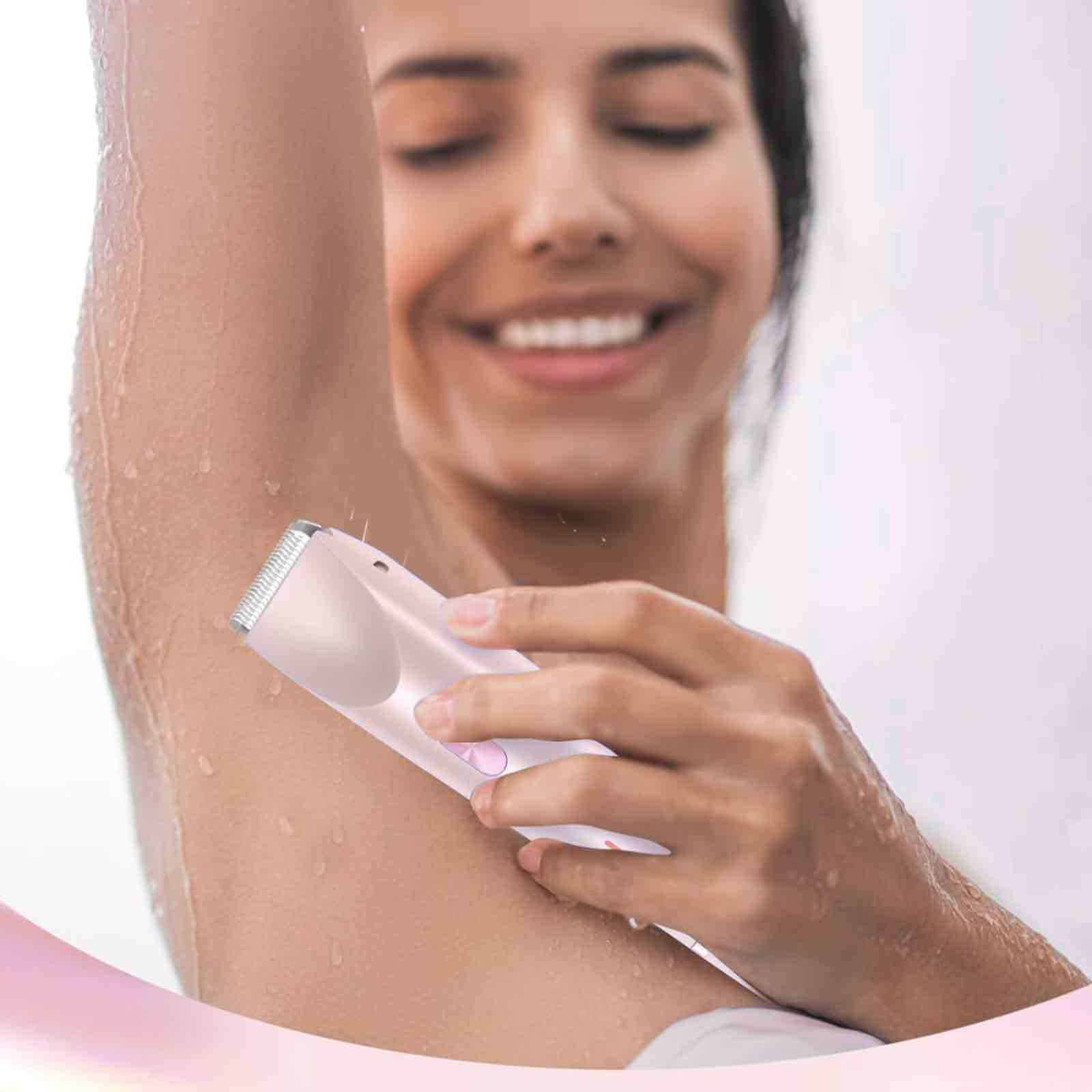 Eine Frau benutzt einen rosa Rasierer unter ihren Achseln, Wassertropfen sind sichtbar.