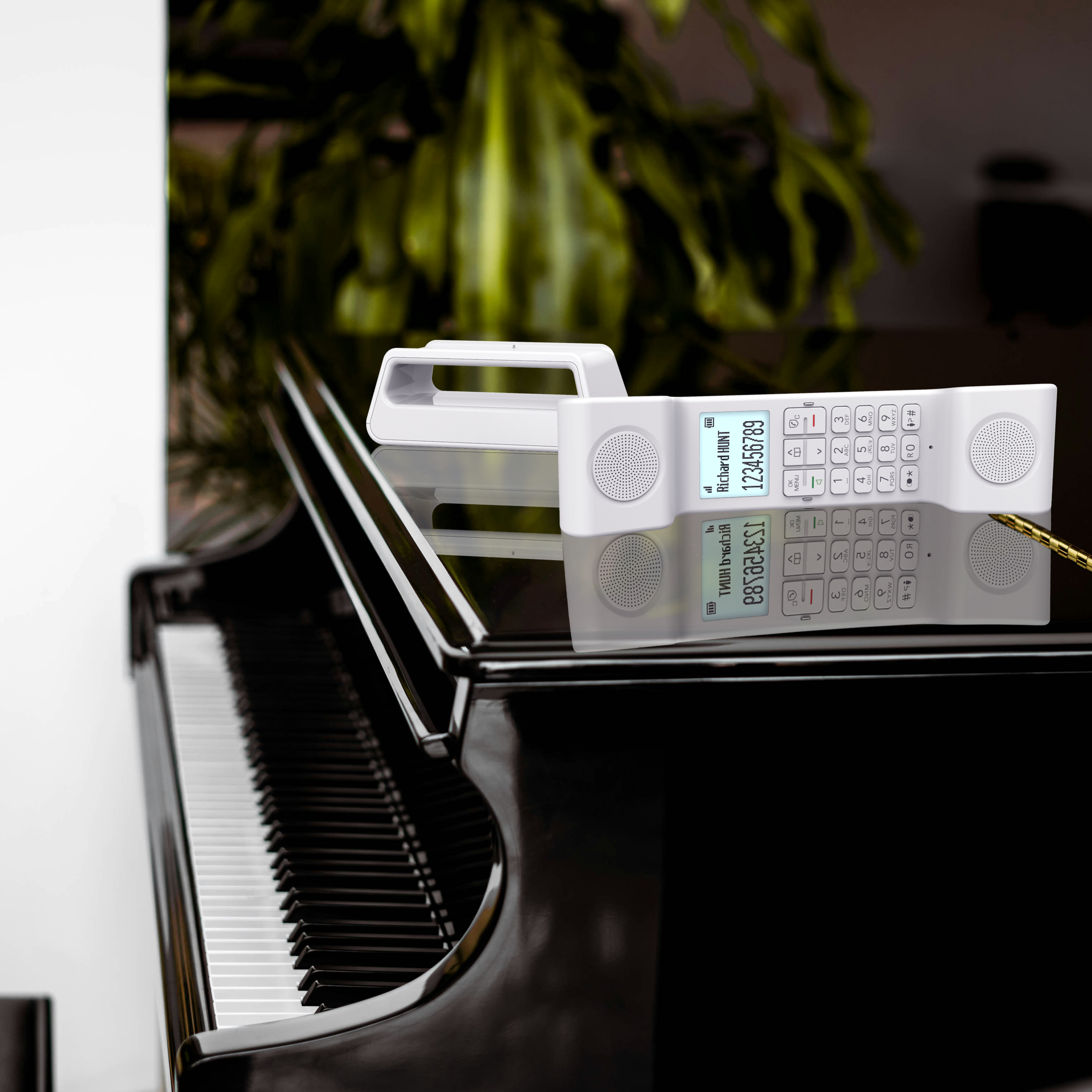 Téléphone sans fil blanc sur un piano noir, avec un reflet miroir et une plante verte.