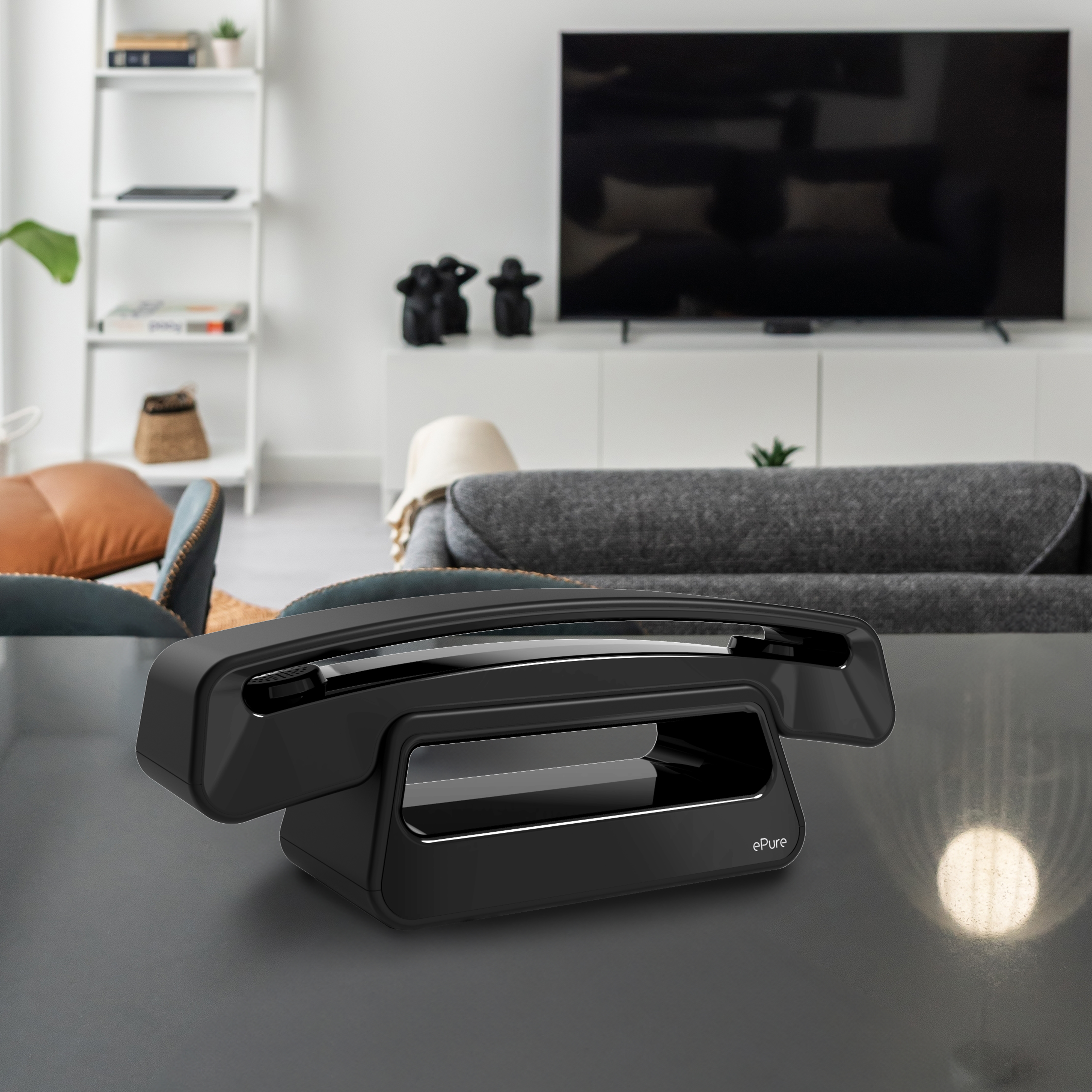 Téléphone ePure noir sur une table dans un salon. Intérieur moderne, TV en arrière-plan.