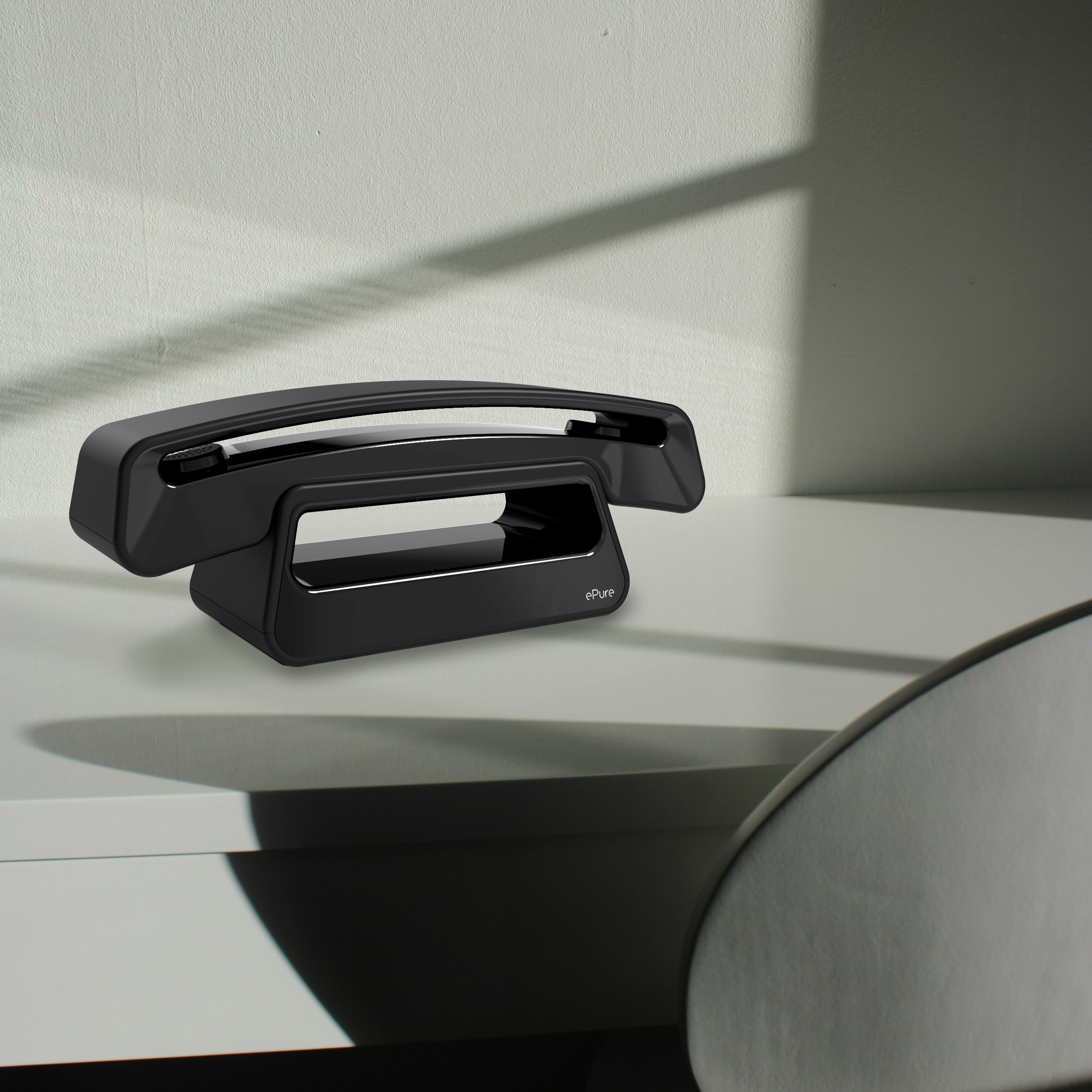 Téléphone ePure noir sur une surface blanche. Cadre minimaliste, fond neutre.