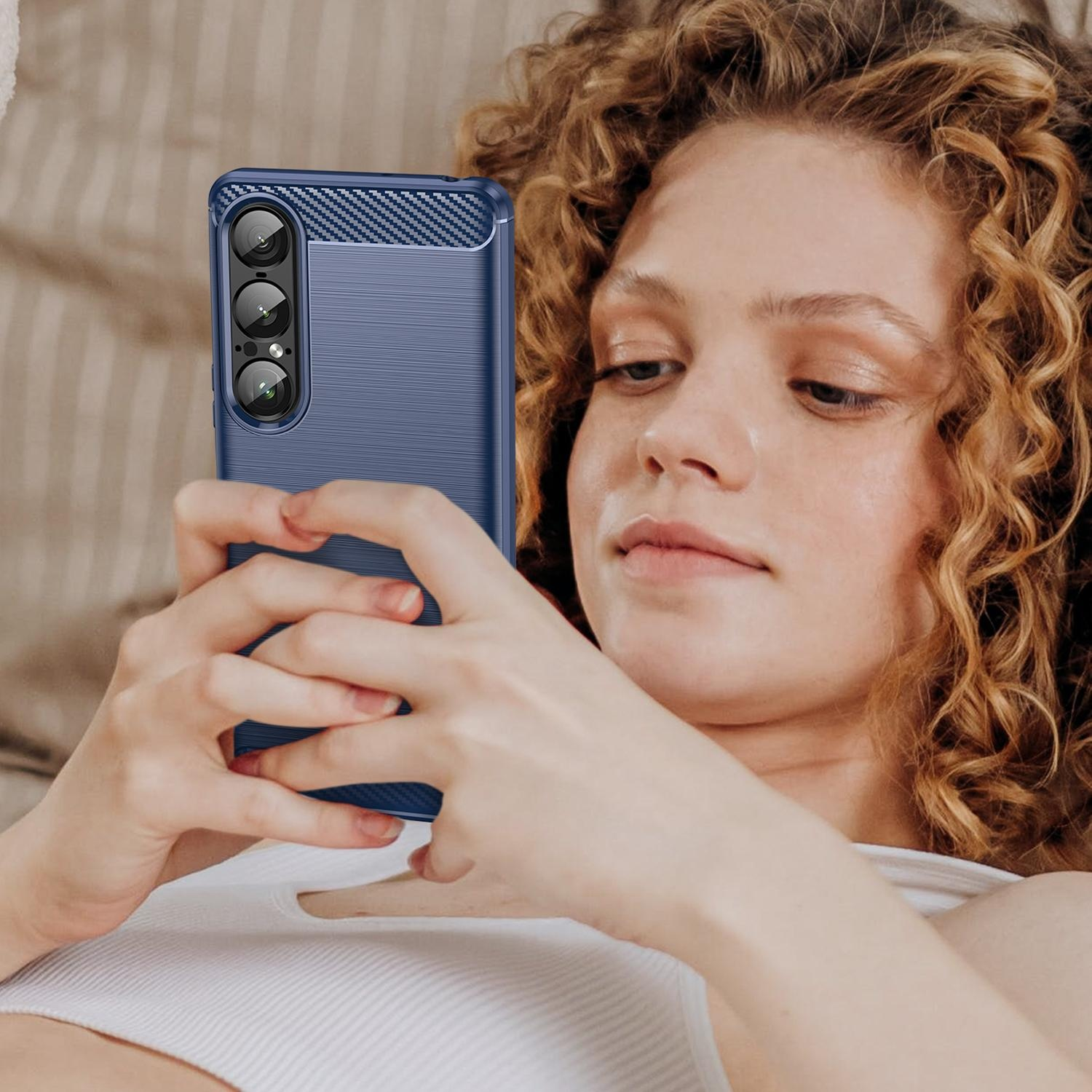 Frau hält Telefon in blauem Gehäuse, blickt auf den Bildschirm.