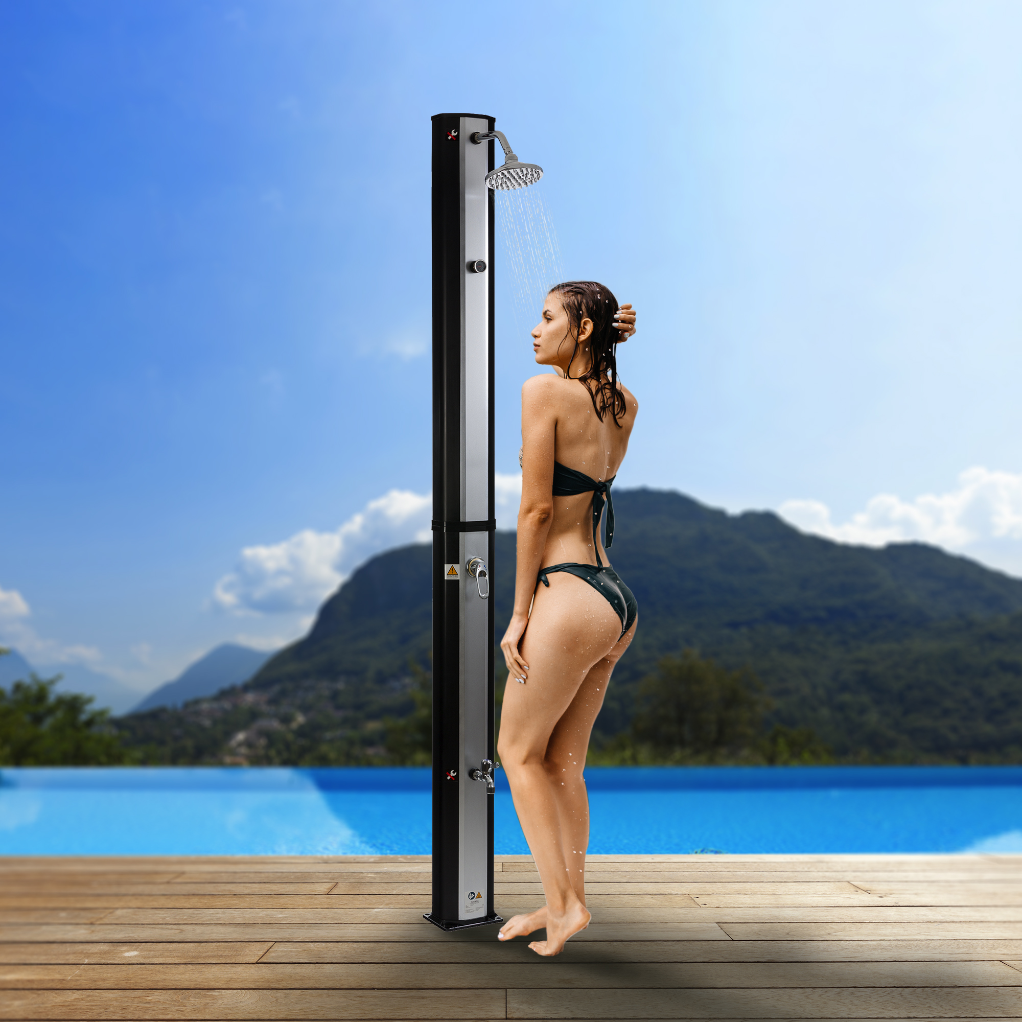 Eine Frau duscht in einer Außendusche. Der Hintergrund zeigt einen Pool und Berge.