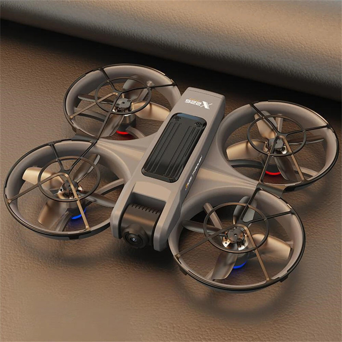 Dron gris con cuatro hélices. Colocado sobre una superficie marrón. Luces azules y rojas visibles.