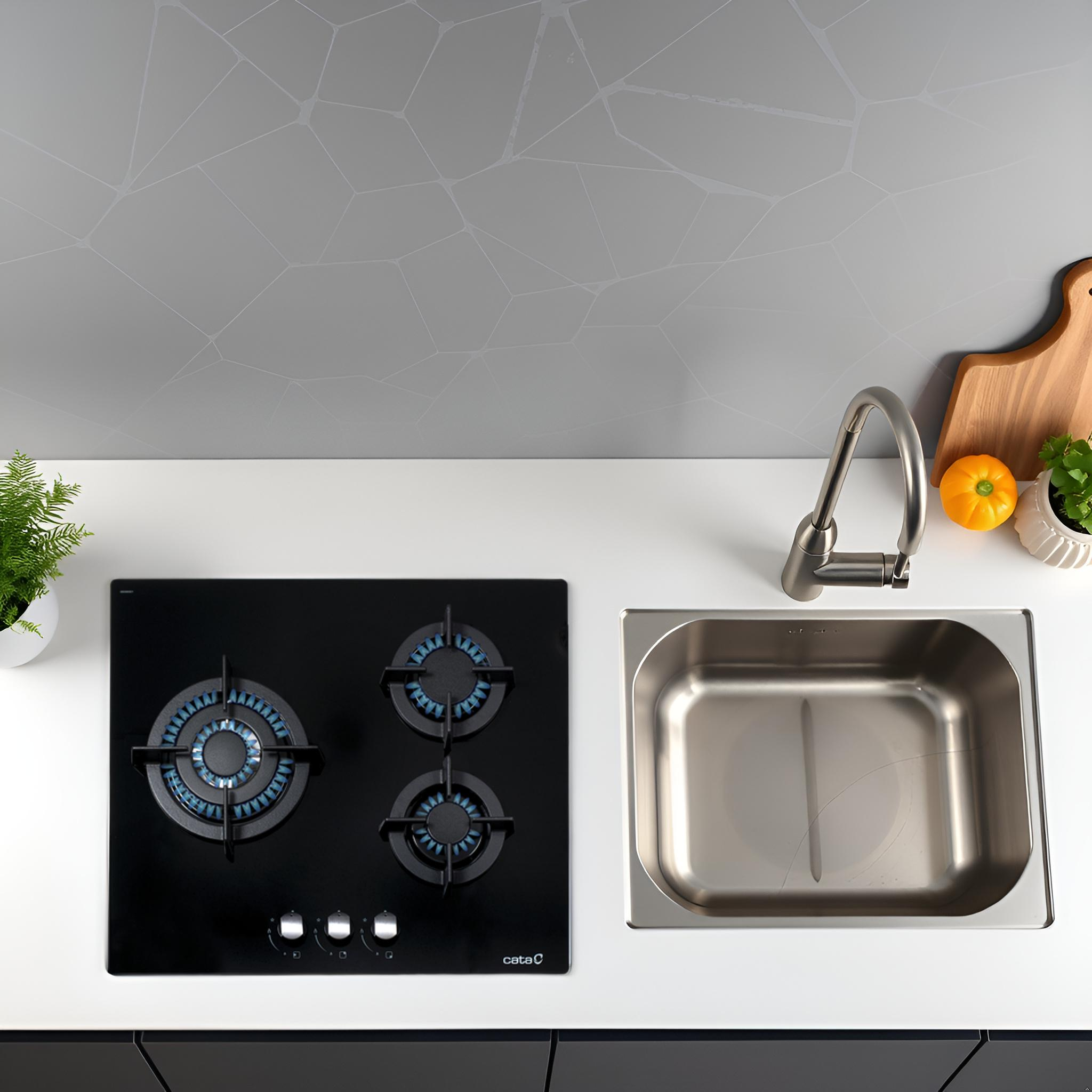 Encimera de cocina con placa y fregadero negros. Diseño moderno con luces azules. Superficie blanca.