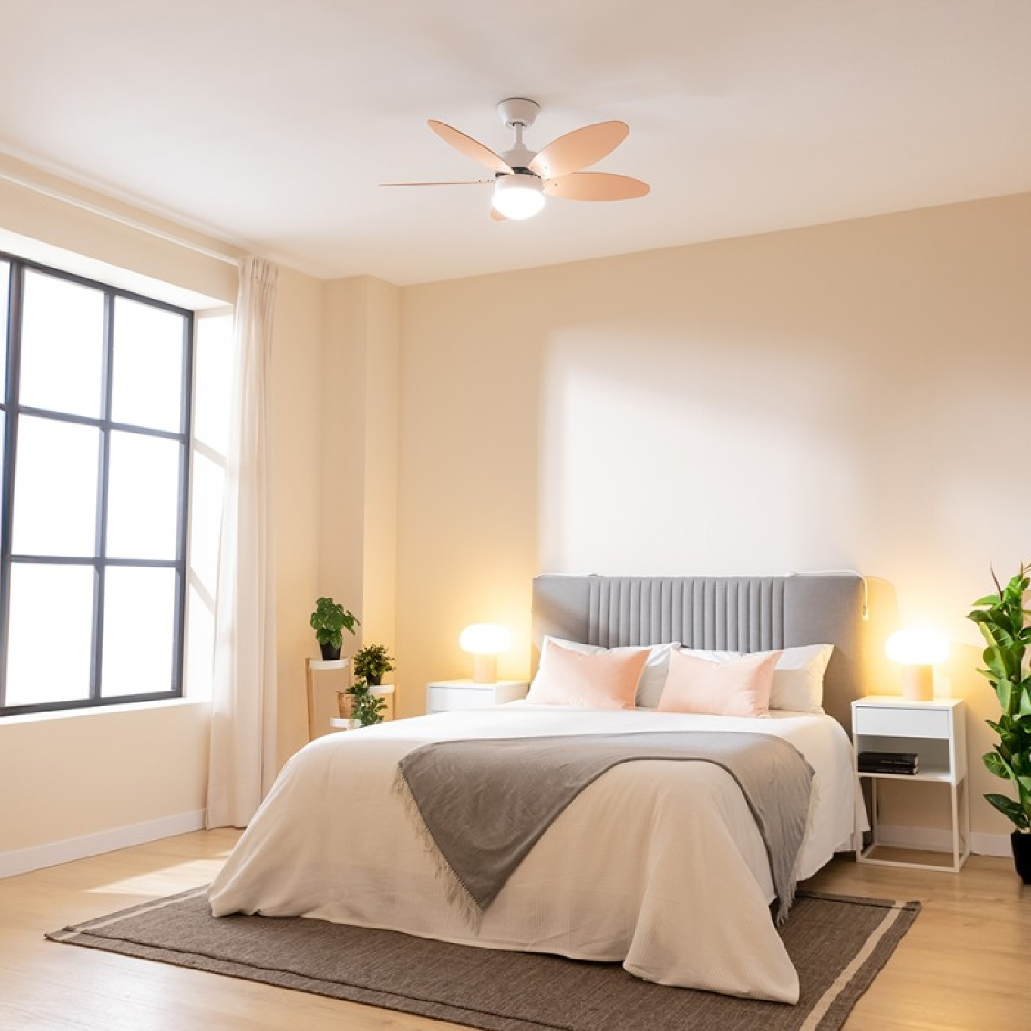 Sypialnia z łóżkiem, szarą ramą i brzoskwiniowym wentylatorem. Stoliki nocne z lampami, oknem i roślinami.