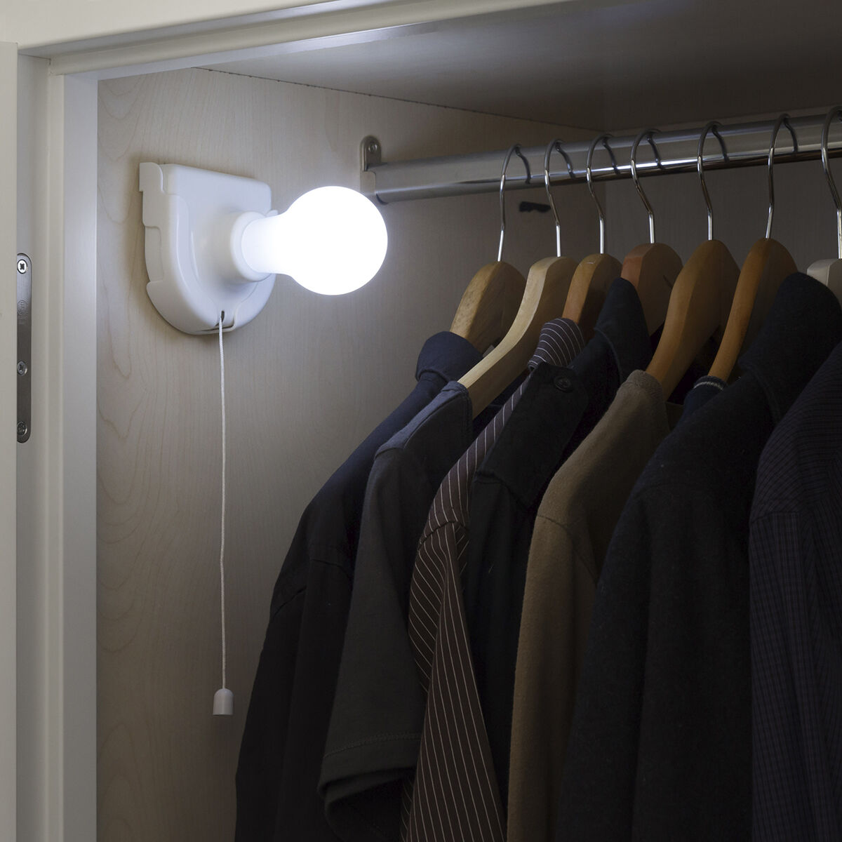 Una lampadina su un muro, con vestiti appesi in un armadio e un cordoncino.