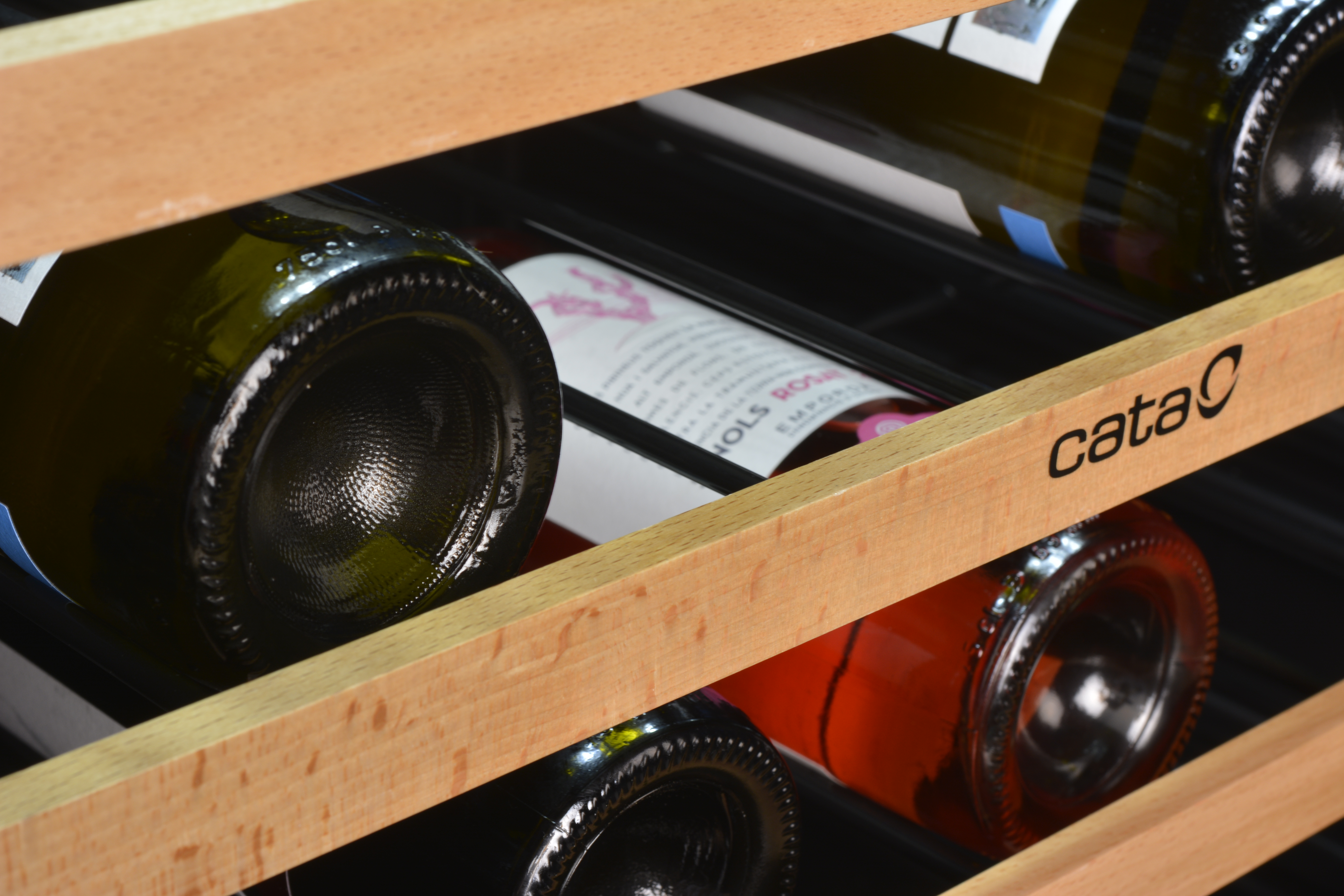 Primer plano de botellas de vino con corchos coloridos en un estante de madera, con la marca "cata".
