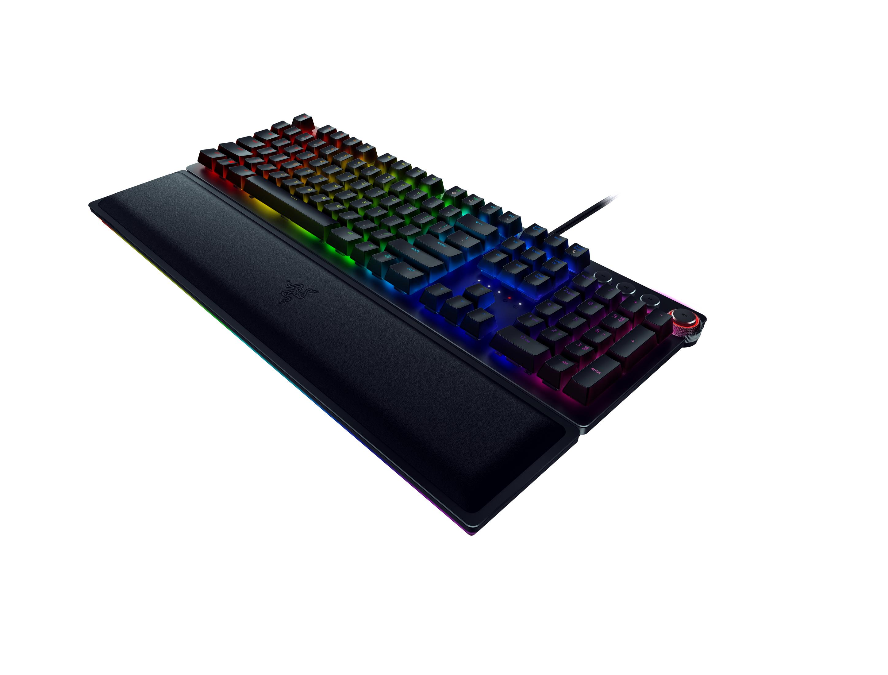 Schwarze Gaming-Tastatur mit Regenbogenlichtern, auf einem Schreibtisch liegend, mit Handgelenkauflage.