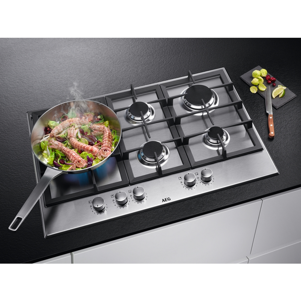 Gotowanie krewetek na patelni na kuchence ze stali nierdzewnej.