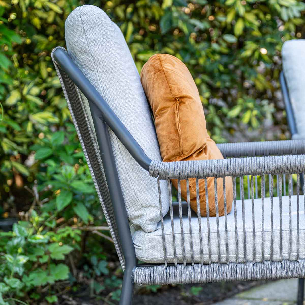 Close-up of chair with rope detailing and pillows.