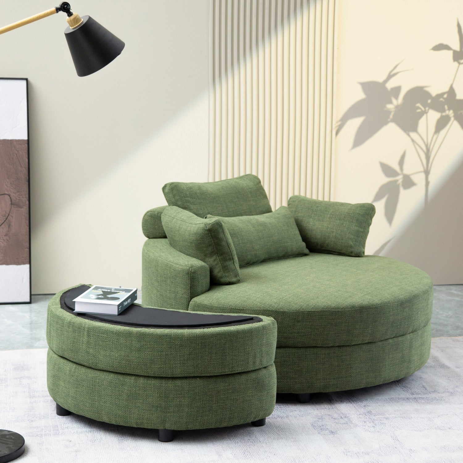 Grünes rundes Sofa mit passendem Hocker und einem schwarzen Beistelltisch mit einem Buch darauf.