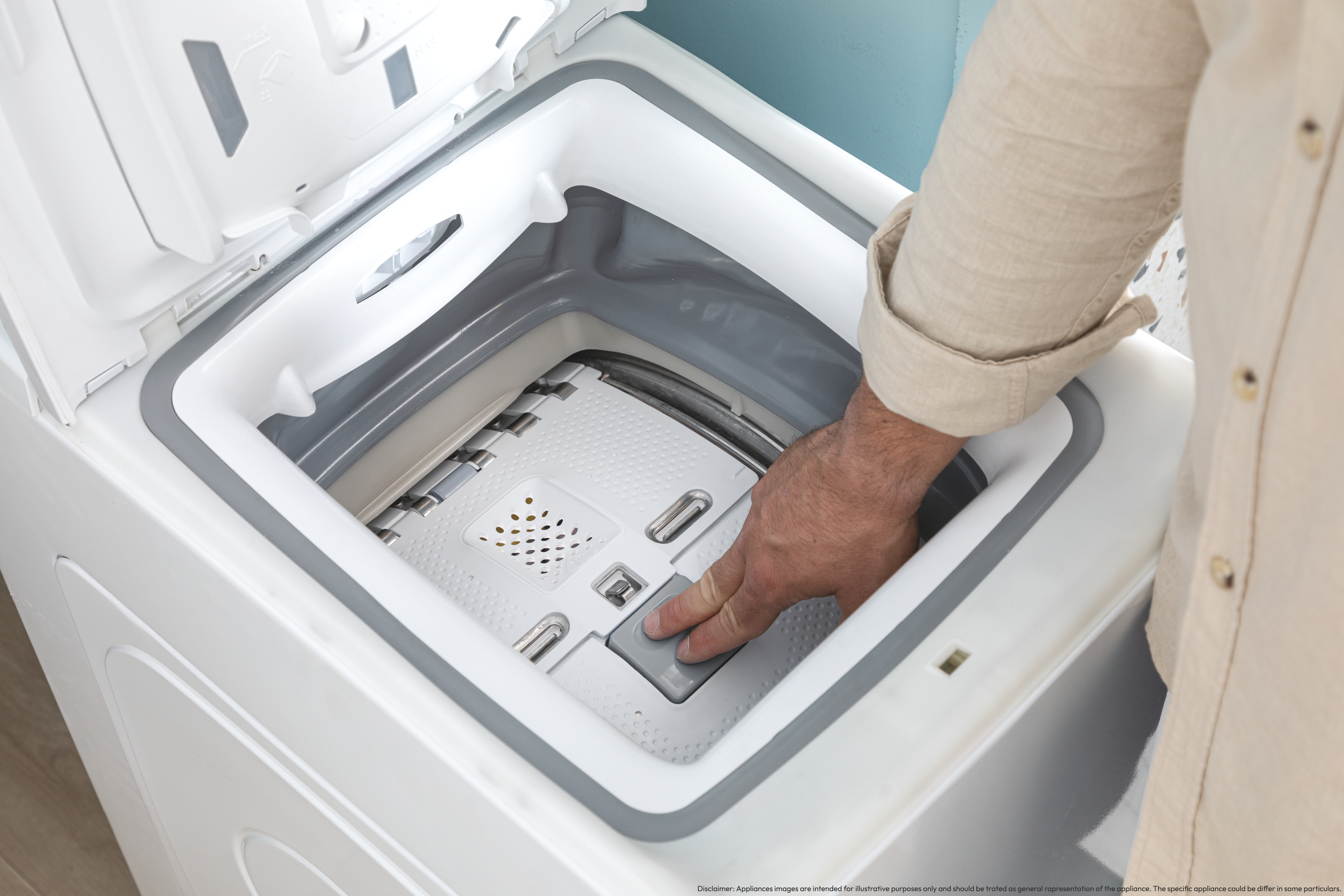 Ręka osoby sięgająca do białej pralki, aby nacisnąć przycisk.