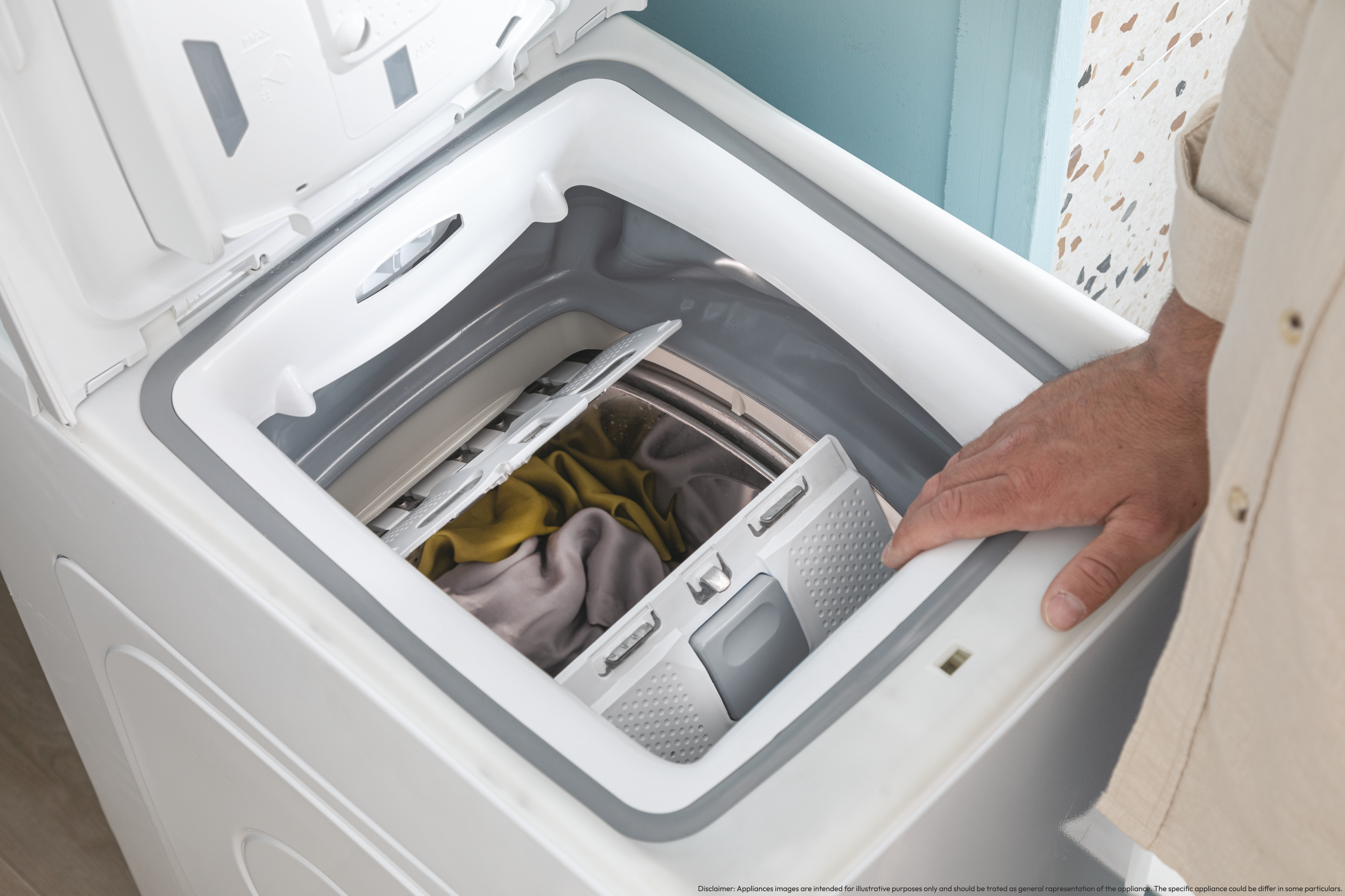 Osoba wkłada ubrania do białej pralki z otwartą pokrywą.