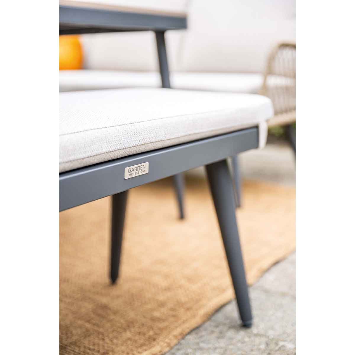 A close-up of a chair with a gray cushion on a brown mat.