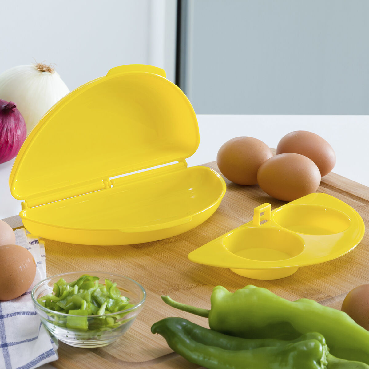 Un fabricante de tortillas amarillo con huevos, verduras y otros ingredientes en una tabla.