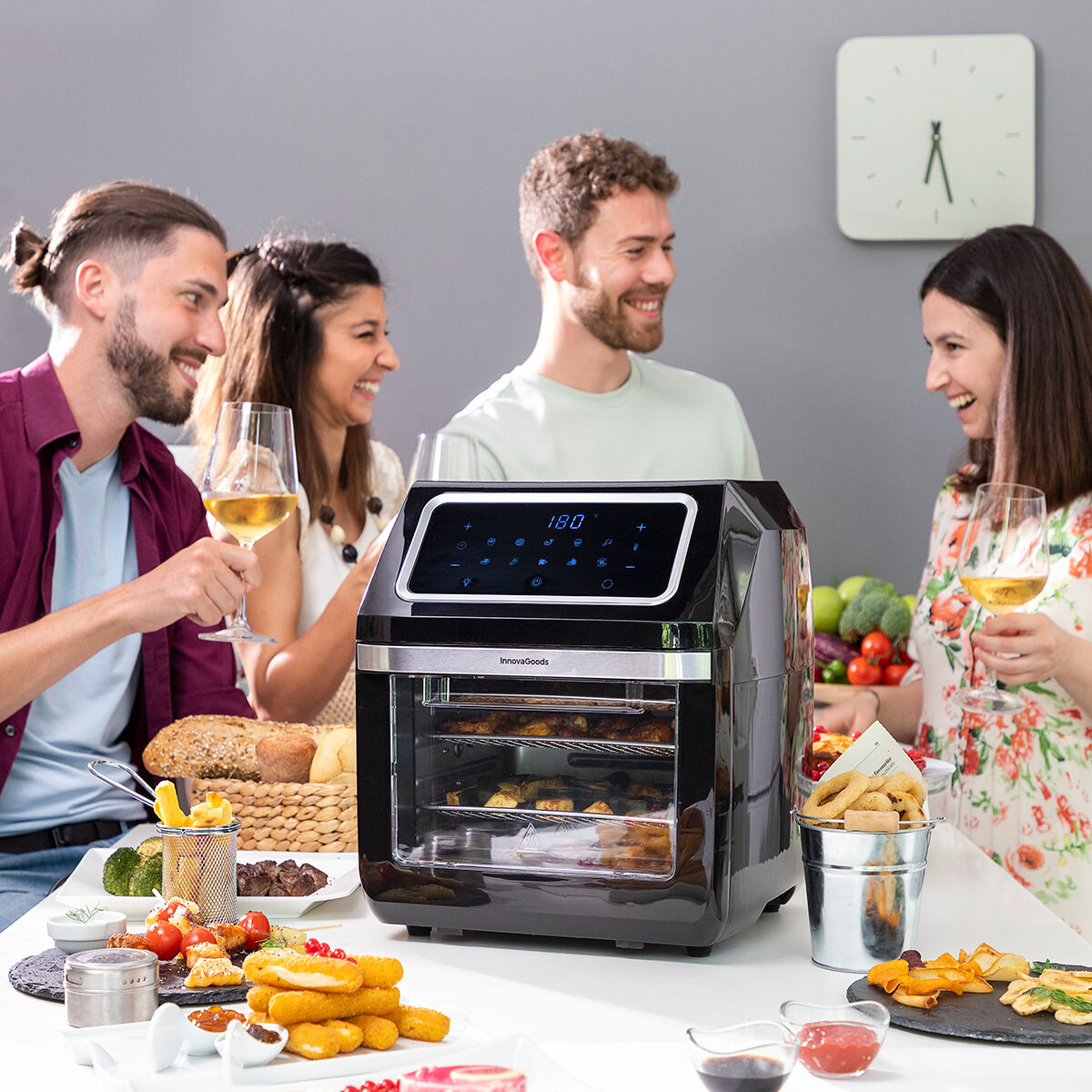Un gruppo di persone brinda con vino vicino a una friggitrice ad aria con cibo.