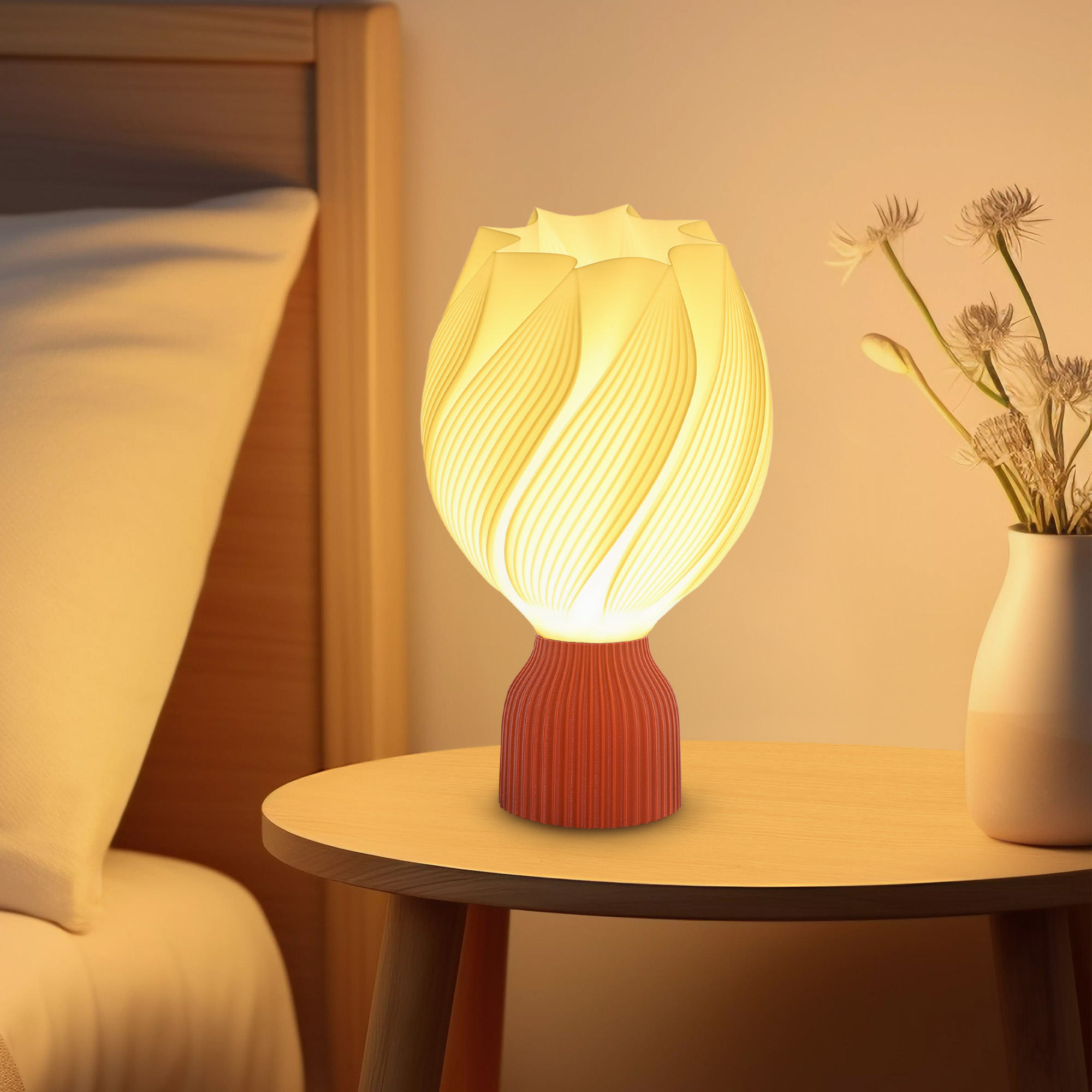 Una lámpara con base roja y diseño de pétalos blanco-amarillo. Está en una mesa de madera junto a un jarrón.