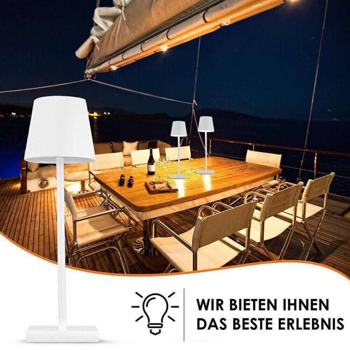 Eine weiße Lampe und zwei weitere auf einem Tisch. Der Hintergrund zeigt eine Yacht bei Nacht. Text: Wir bieten das beste Erlebnis.