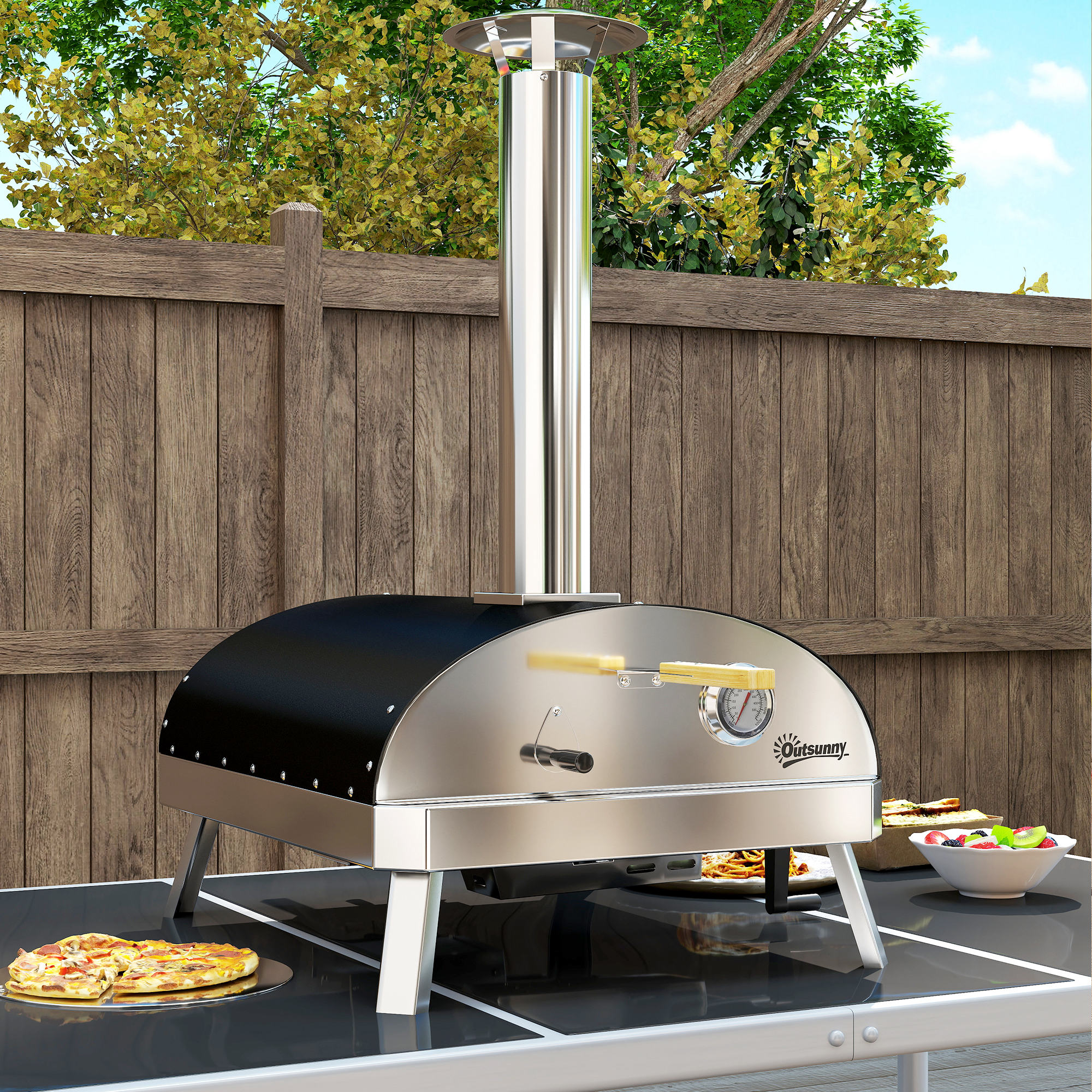Horno de pizza al aire libre sobre una mesa. El horno es plateado y negro. Hay pizza y un cuenco de ensalada.