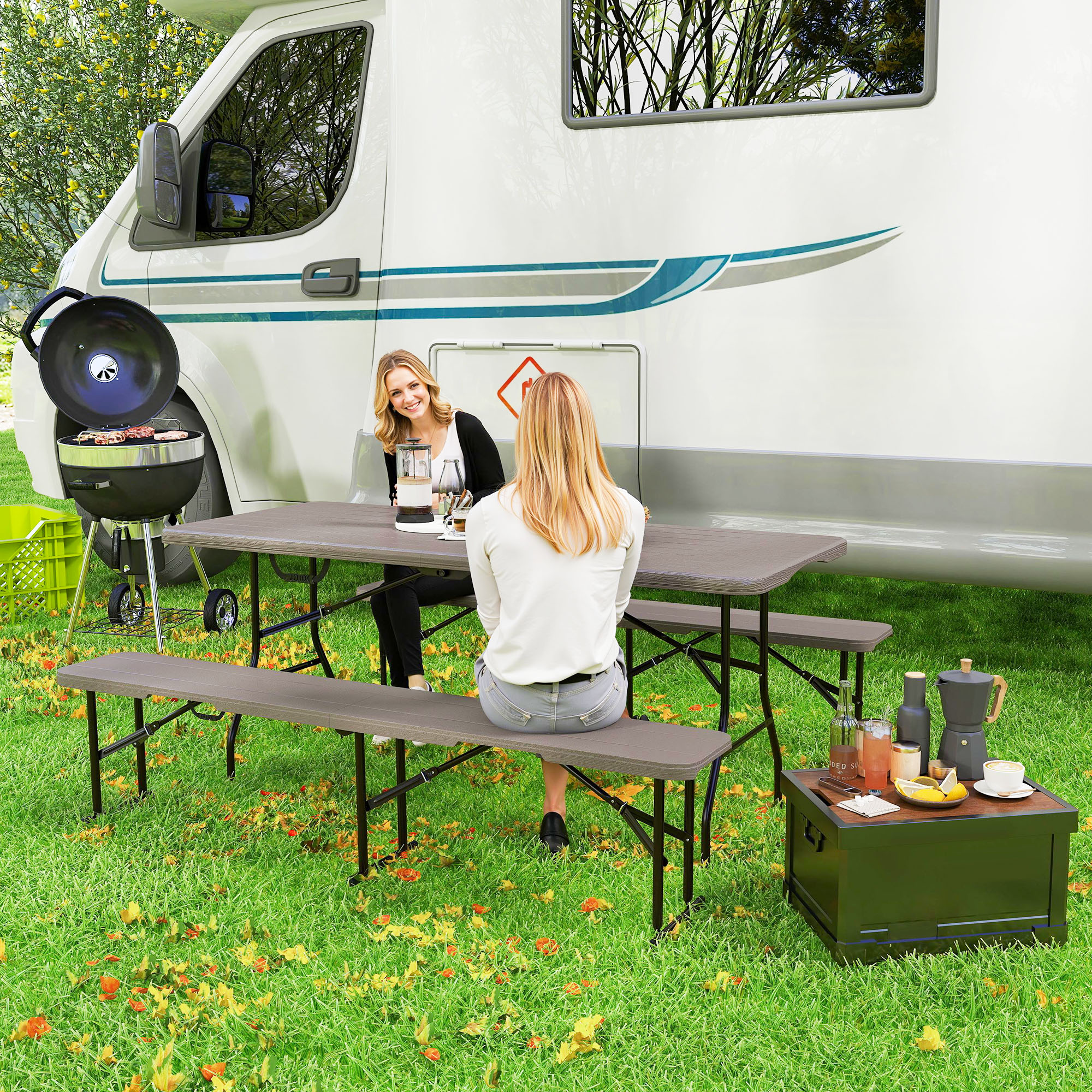 Escena de picnic con mesa y bancos. Dos mujeres sentadas en la mesa cerca de una autocaravana.