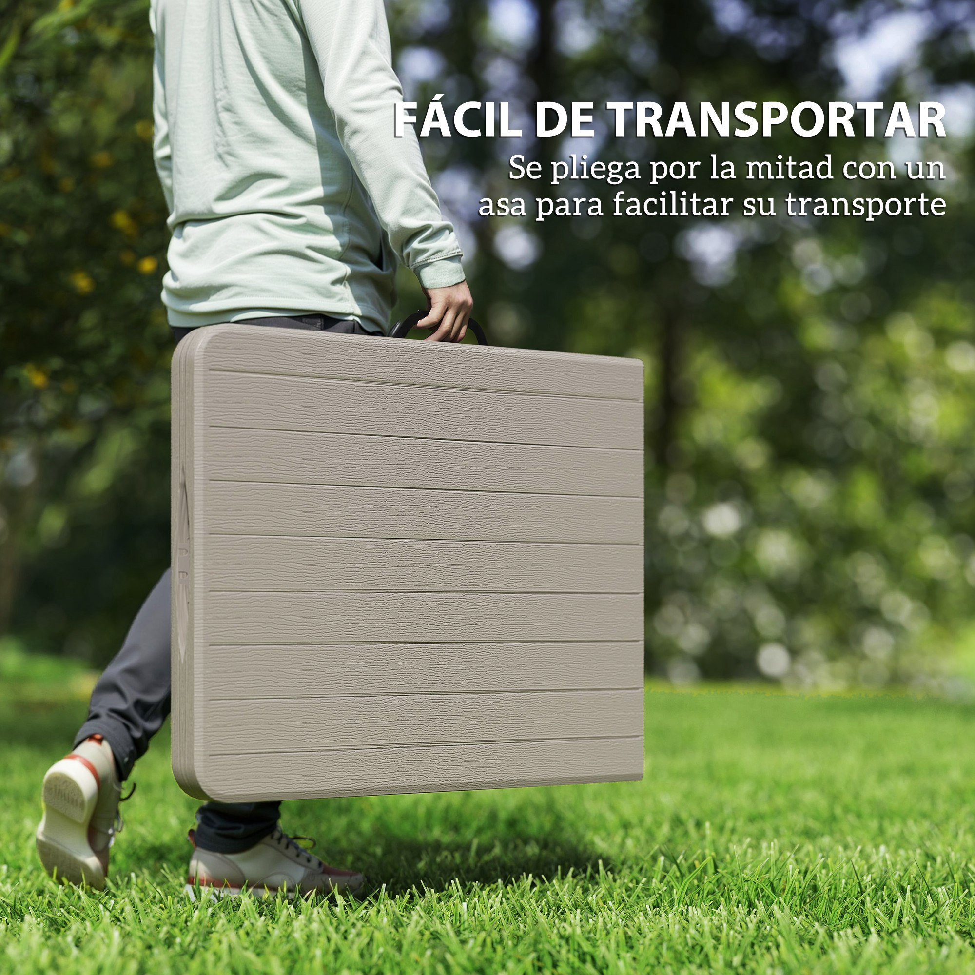 Una persona lleva una mesa plegable en un campo de hierba verde.