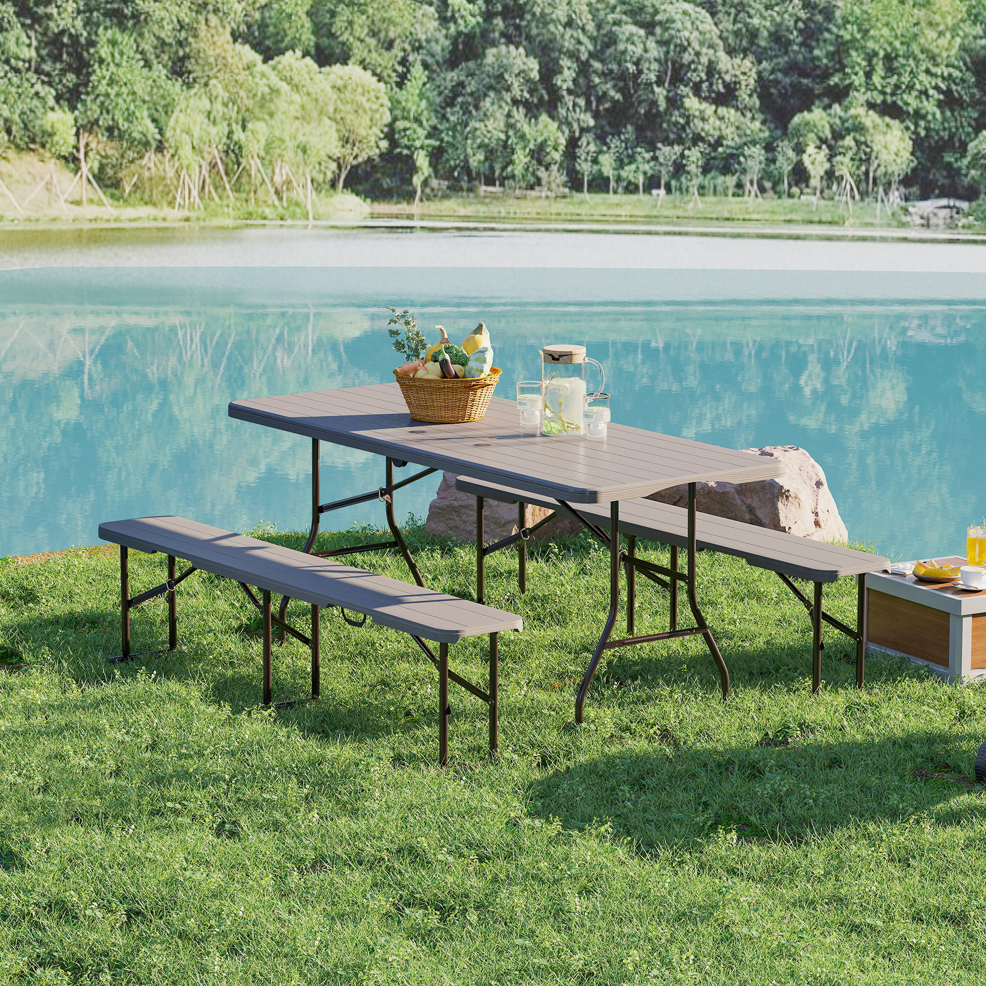 Un juego de mesa de picnic con comida y bebida en un campo de hierba verde cerca del agua.
