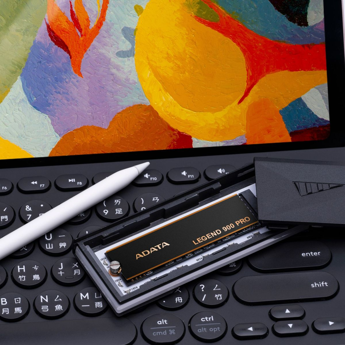 Gros plan sur un clavier avec un boîtier noir ouvert contenant un SSD noir et doré.