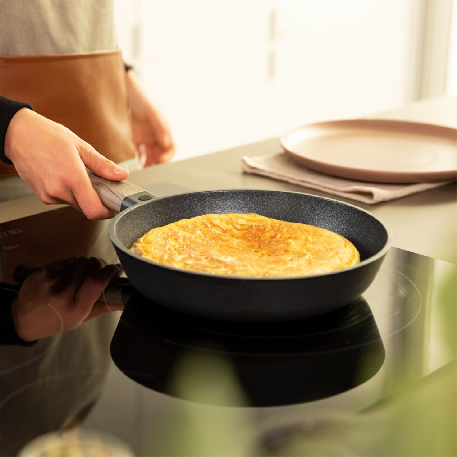 Una persona che tiene una padella con una frittata su un fornello.