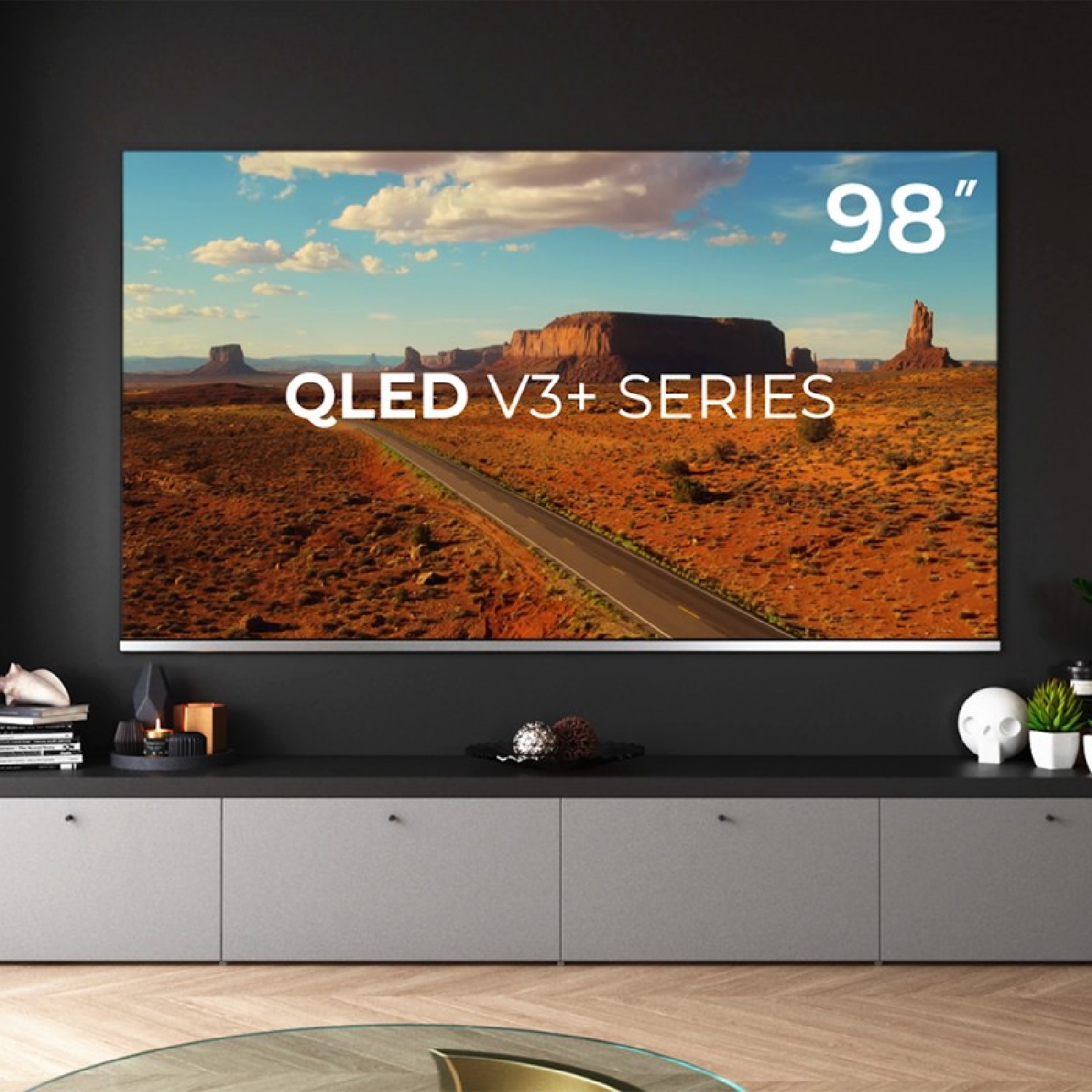 Un televisor grande que muestra un paisaje desértico, con el texto 'QLED V3+ SERIES 98"'.