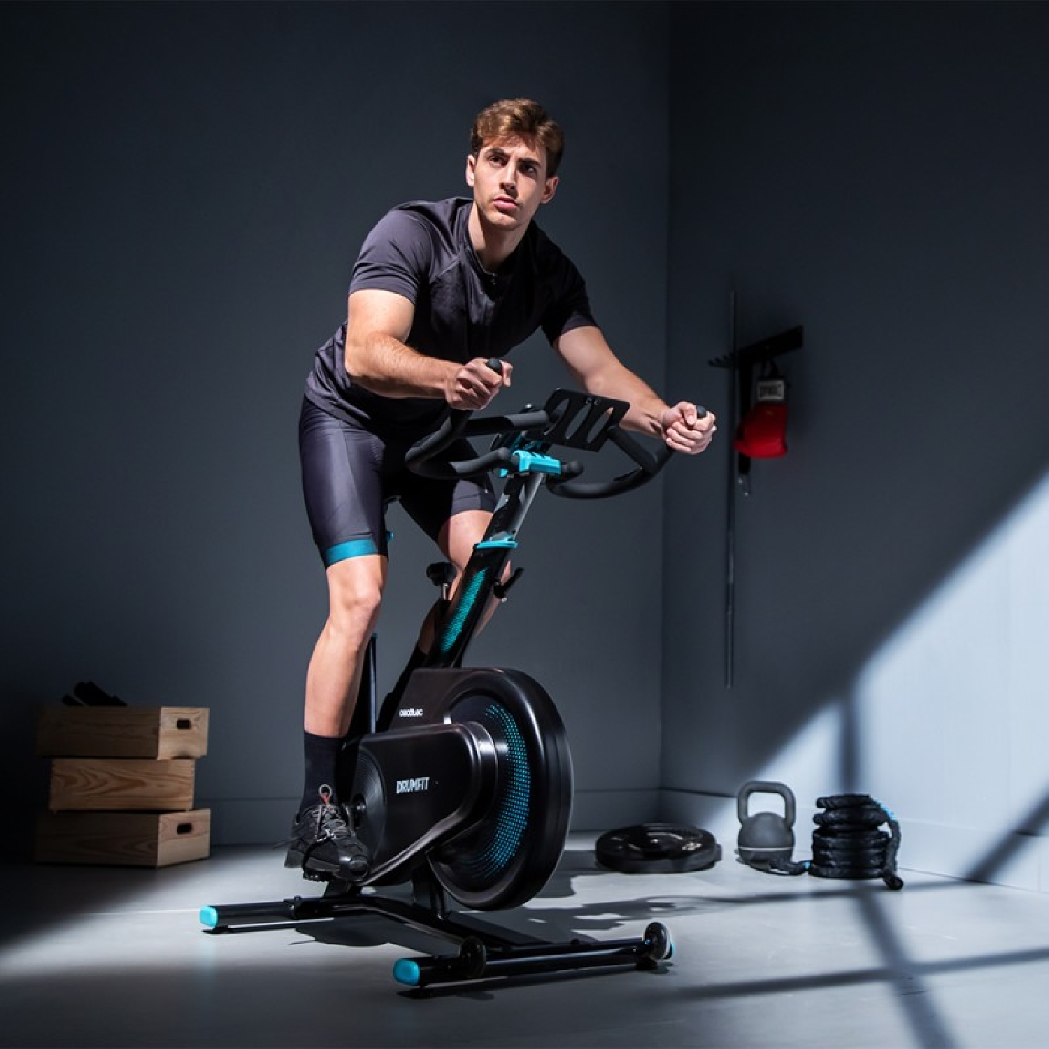 Un uomo su una cyclette in palestra. Indossa abiti da allenamento e guarda in alto.