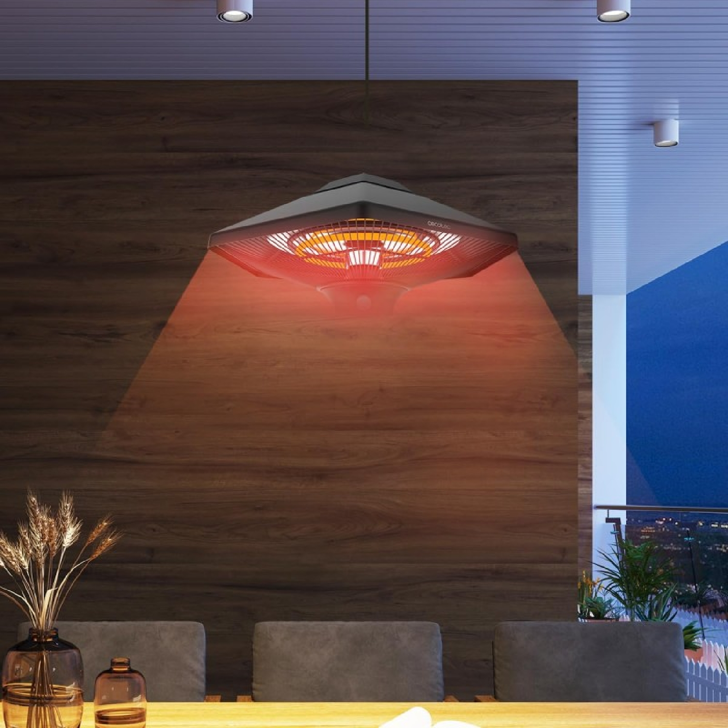 Un calentador colgante negro y cuadrado ilumina una mesa de comedor. El fondo es una pared de madera y luces de la ciudad.