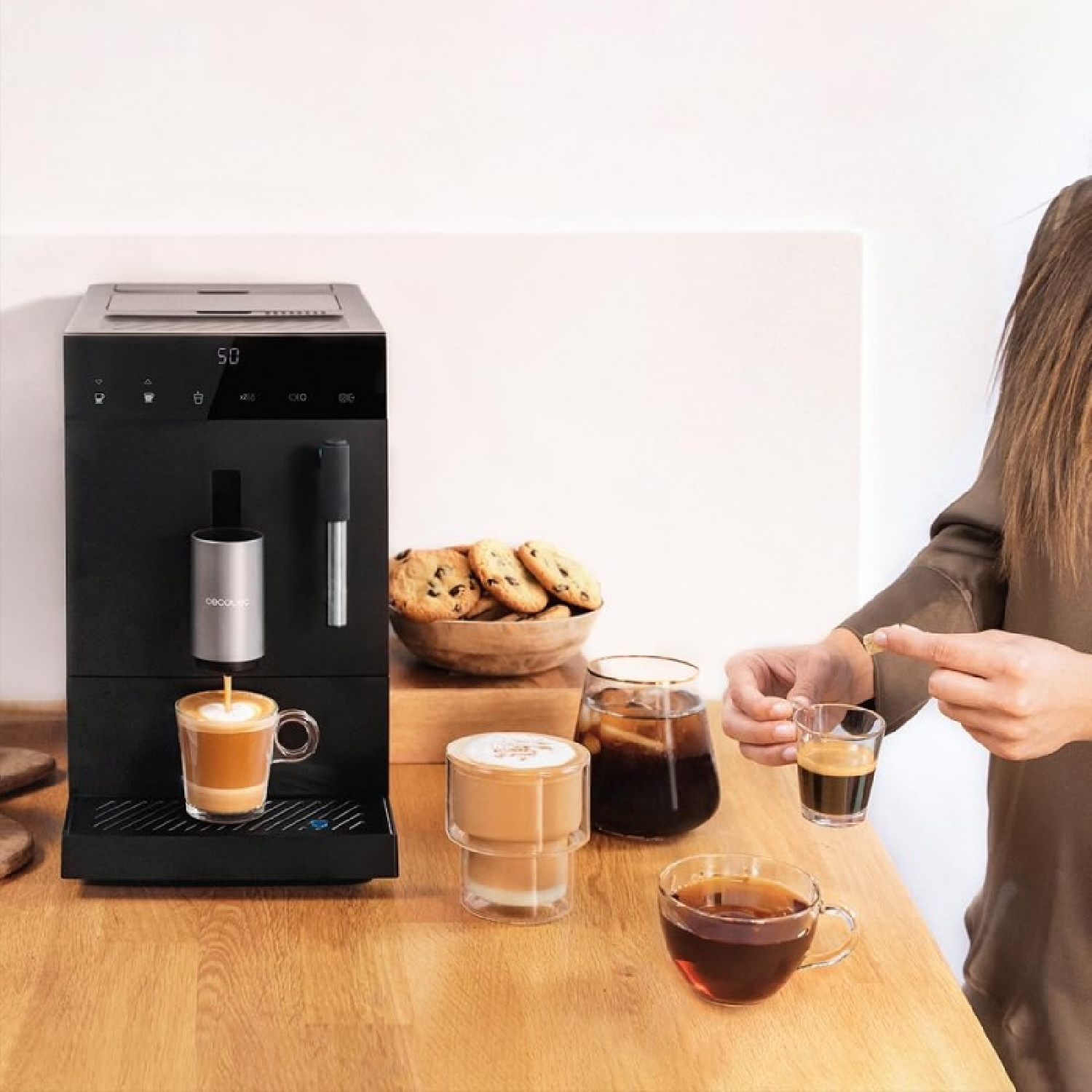 Una persona che fa il caffè. Sono visibili una macchina, tazze, biscotti e bevande.