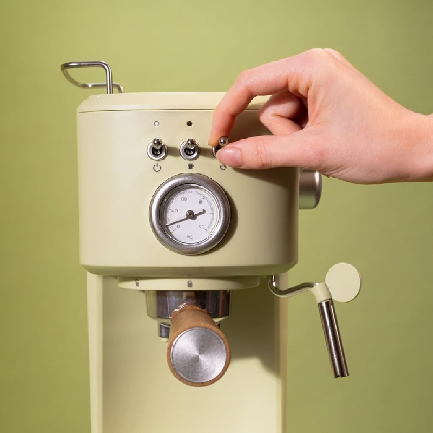 Ręka osoby włączająca przełącznik w kremowym ekspresie do kawy ze srebrnym wskaźnikiem i drewnianym uchwytem.