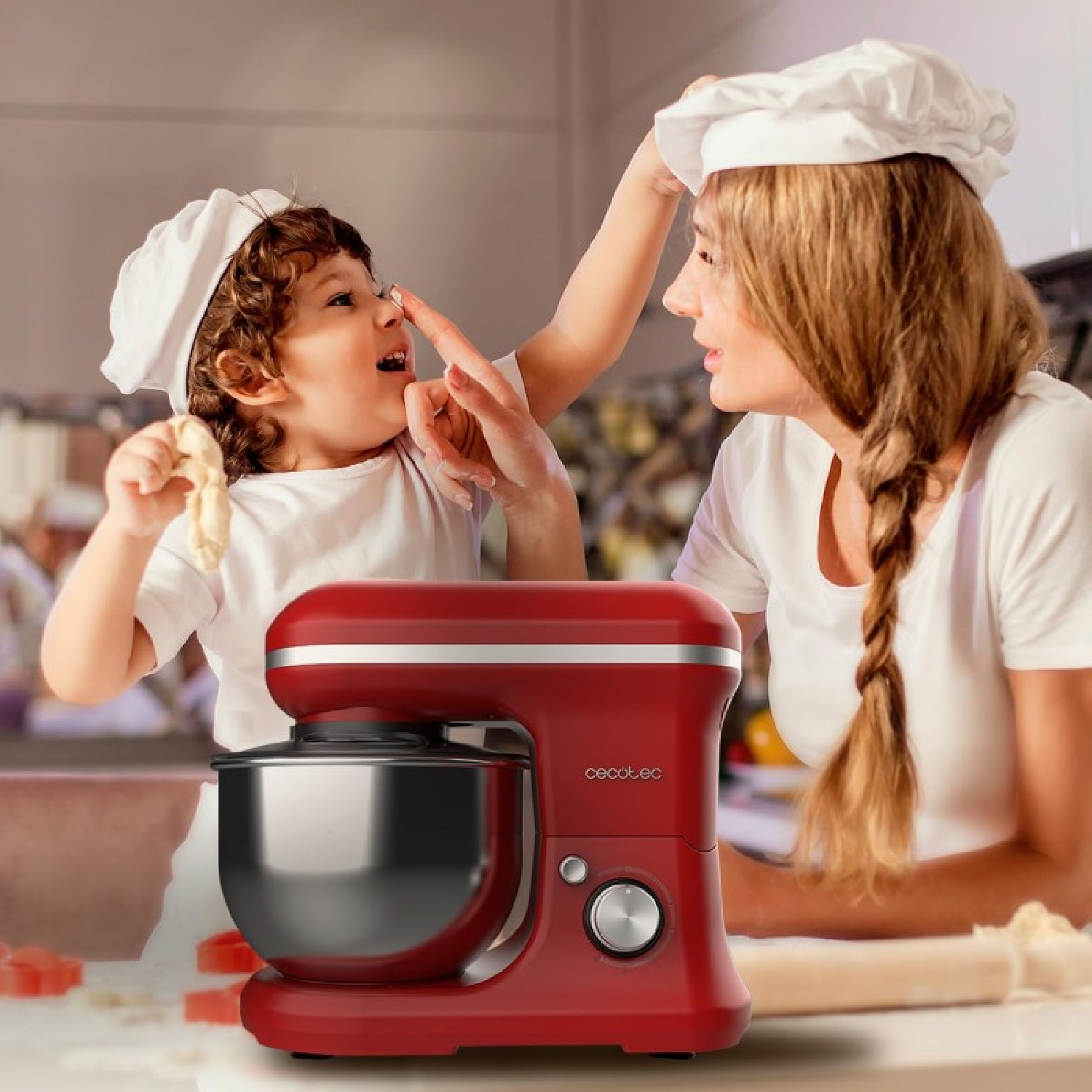 Un robot da cucina rosso con un bambino e una donna sullo sfondo.