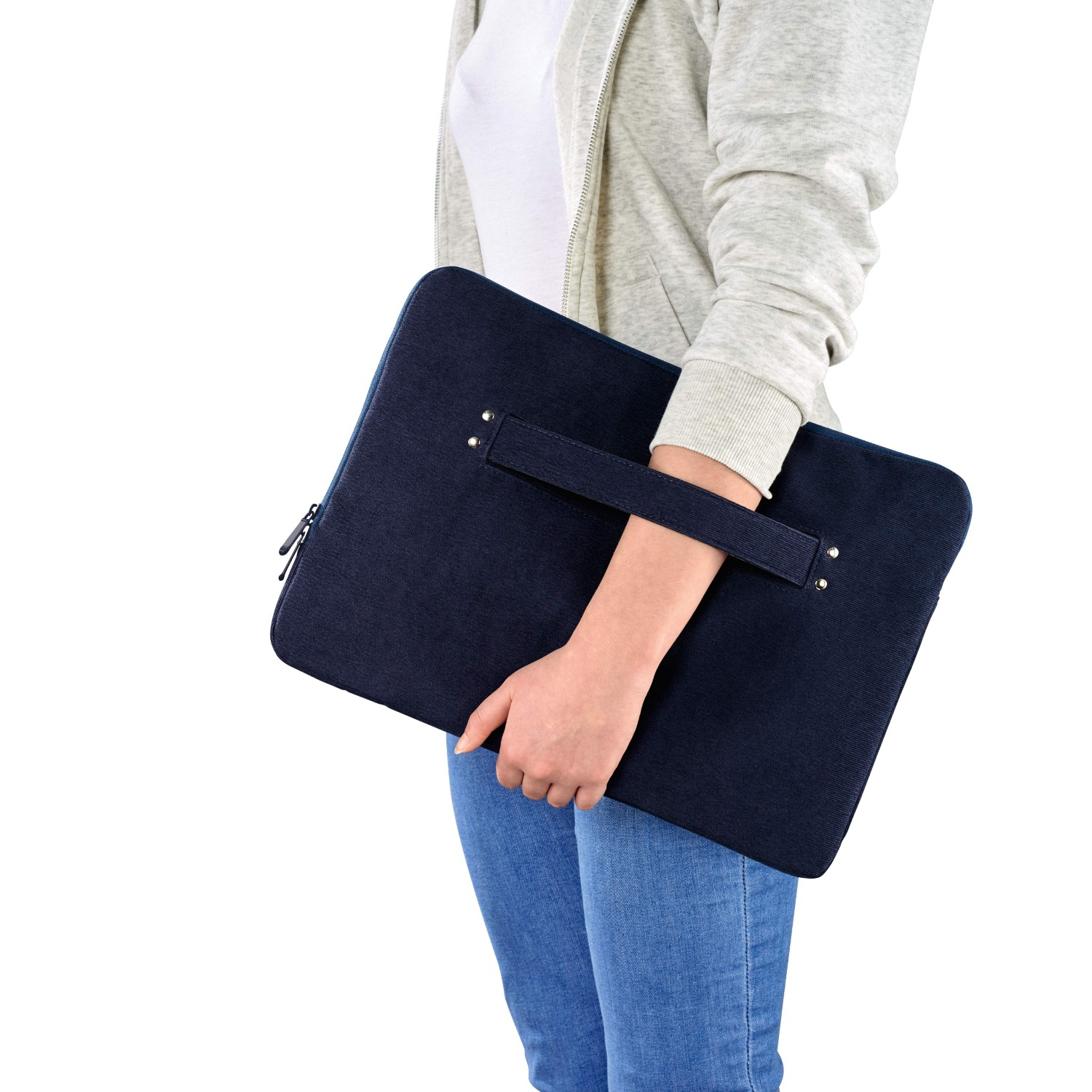 Osoba trzymająca niebieską torbę na laptopa z uchwytem. Białe tło, dżinsy i szara bluza z kapturem. Torba na zamek.